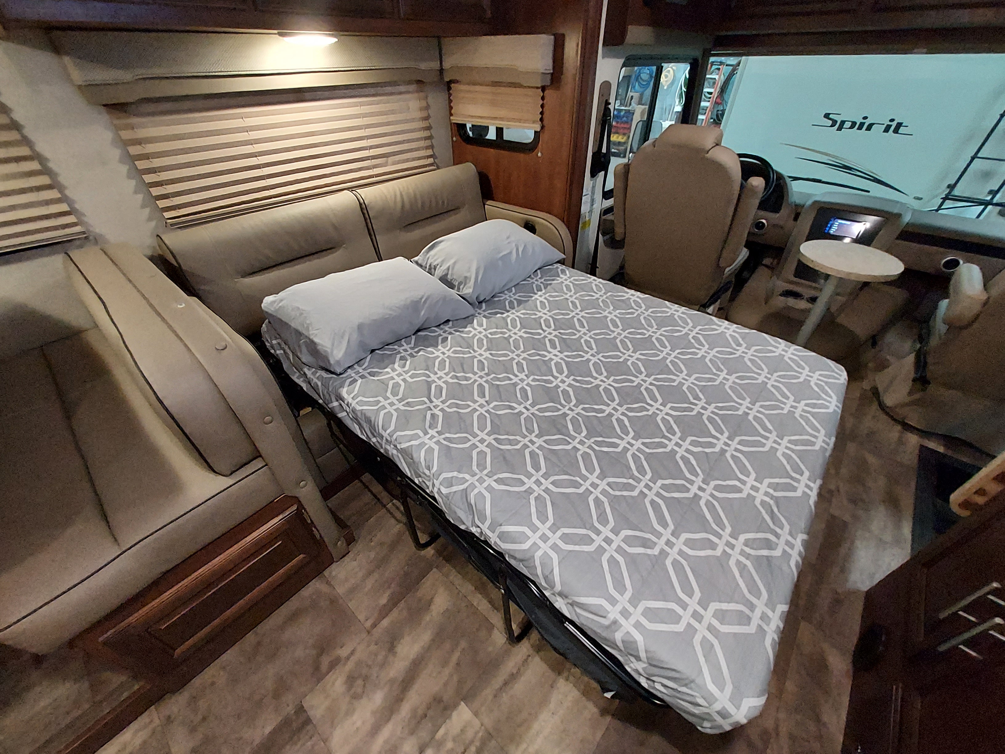 Spacious RV rental interior featuring a comfortable convertible sofa bed with gray bedding. The front cockpit area is also visible.. Forest River Georgetown 3 Series 30X3 2017
