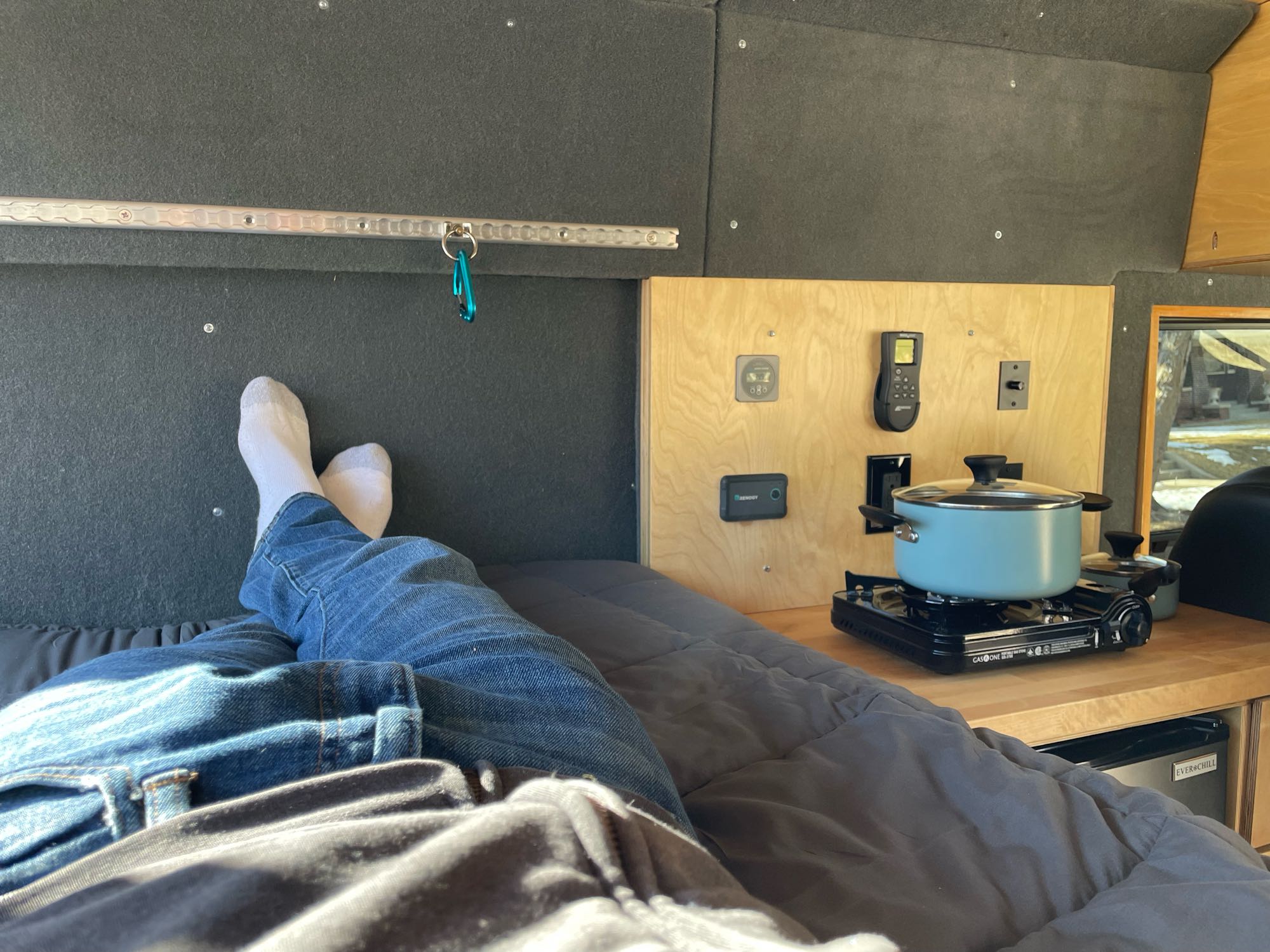 Enjoying an RV rental: comfortable sleeping area, handy cooking stove with a pot, and integrated storage in this cozy camper van.. Ram Promaster 2500 2021