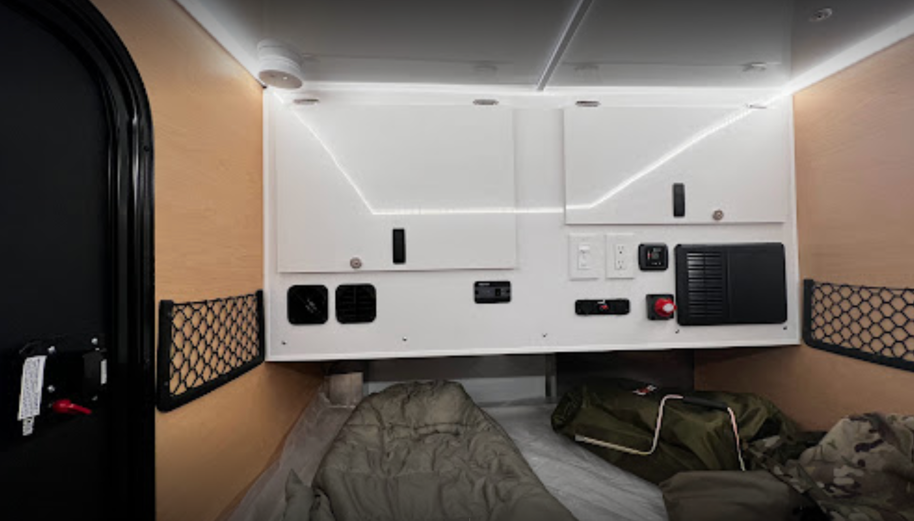 rv rental camper interior: wood walls, overhead cabinets with LED lights, control panel, mesh storage, and comfortable sleeping area.. BOREAS XT XT 2022