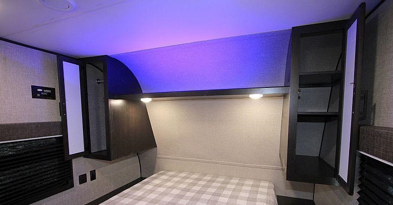 Cozy RV rental bedroom featuring a comfortable bed, smart overhead storage, and stylish purple accent lighting.. Jayco Jay Flight 2022