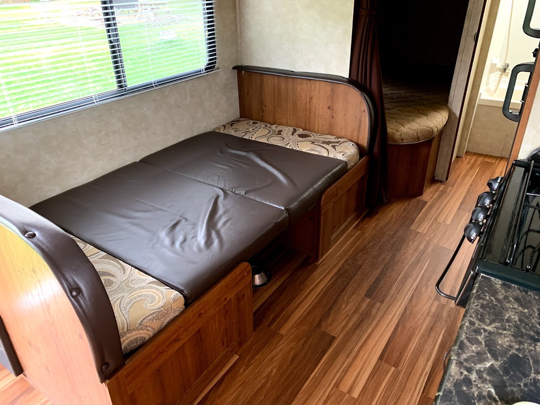 Inside an RV rental: view of the main living area with a convertible bench/bed, kitchen, and bathroom access. Ready for road trips.. Gulf Stream Amerilite 2015
