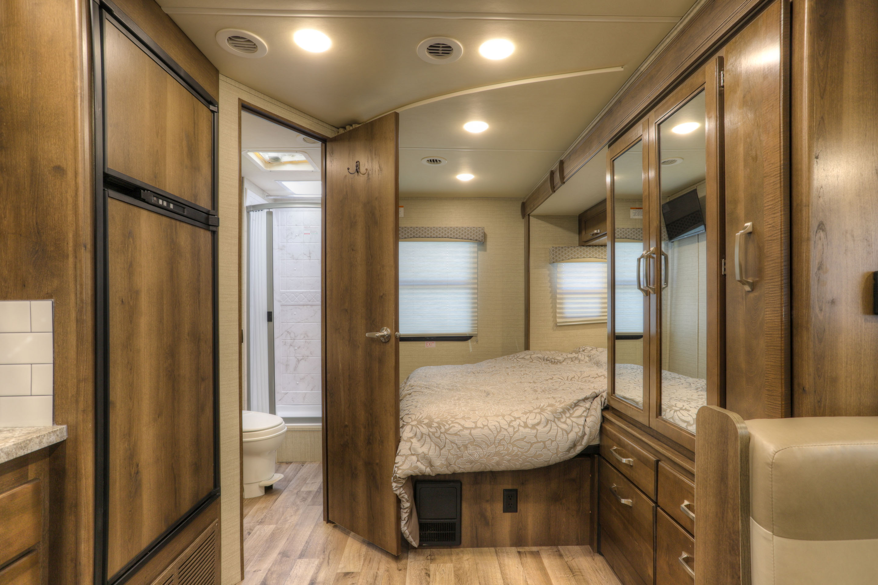 Tour this RV rental's efficient interior featuring a bedroom, bathroom, and kitchen with integrated refrigerator on wood floors.. Jayco Melbourne 2020