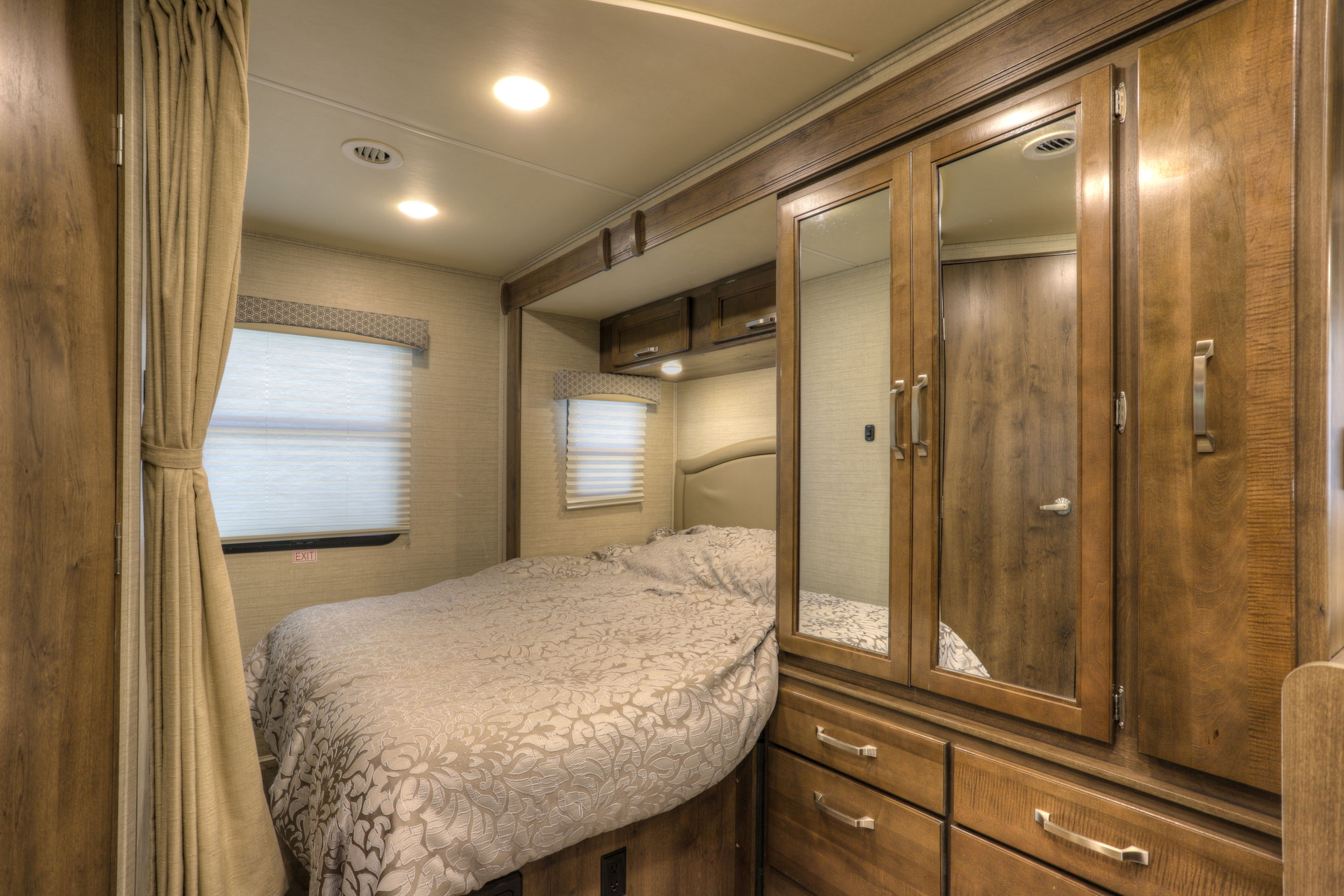 Cozy RV rental bedroom with a bed, patterned comforter, window blinds, and mirrored wardrobe.. Jayco Melbourne 2020