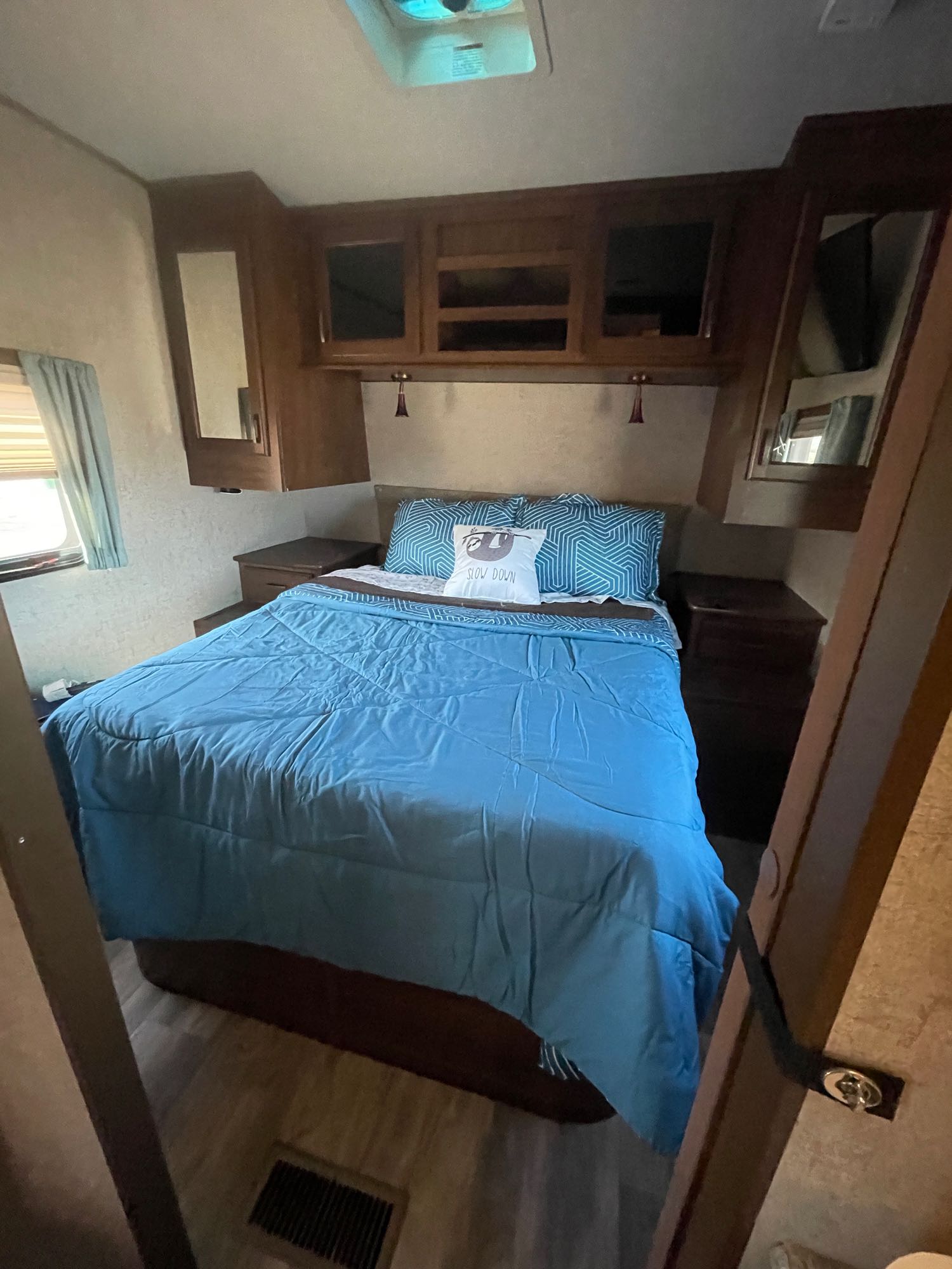 Cozy RV rental bedroom with a blue bed, overhead cabinets, and nightstands. Perfect sleeping area for your travels.. Other Light 2017
