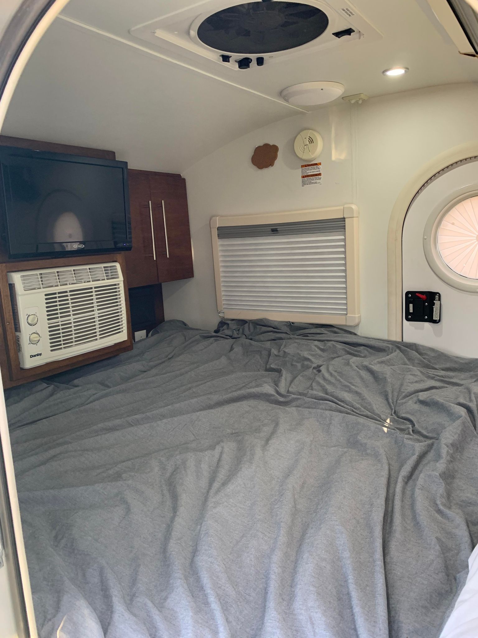 Experience a compact RV rental interior with a large bed, TV, and AC unit for comfy travel.. Other Other 2018
