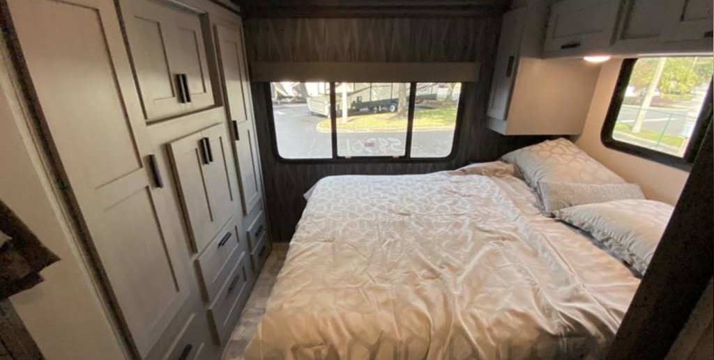 Cozy RV rental bedroom featuring a comfortable bed, window view of the outside, and integrated storage cabinets.. Forest River Solera 2022