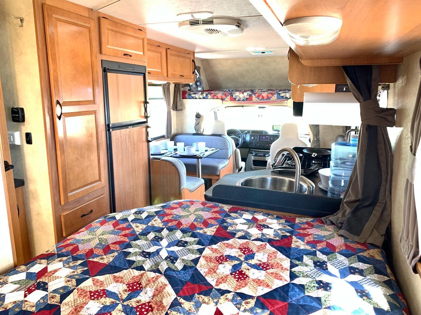 Explore this rv rental's spacious interior: a cozy quilted bed, full kitchen, and dining area.. Thor Motor Coach Four Winds Majestic 2016
