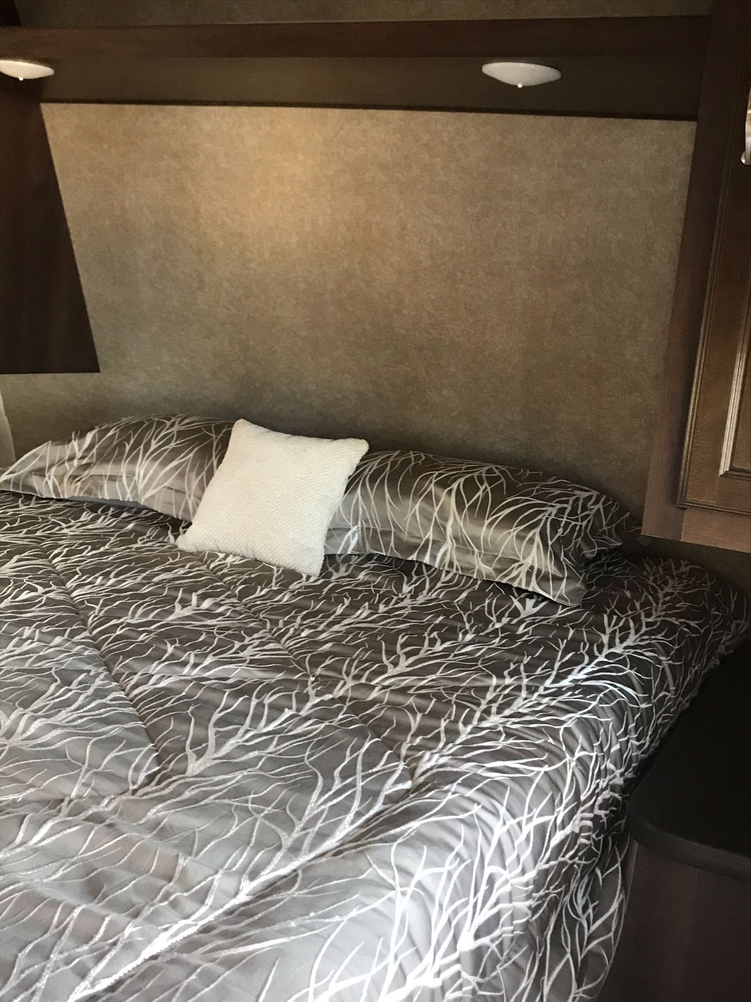 Cozy RV rental bedroom featuring stylish branch-patterned bedding, a soft white accent pillow, and warm lighting.. Jayco Jay Flight 2018