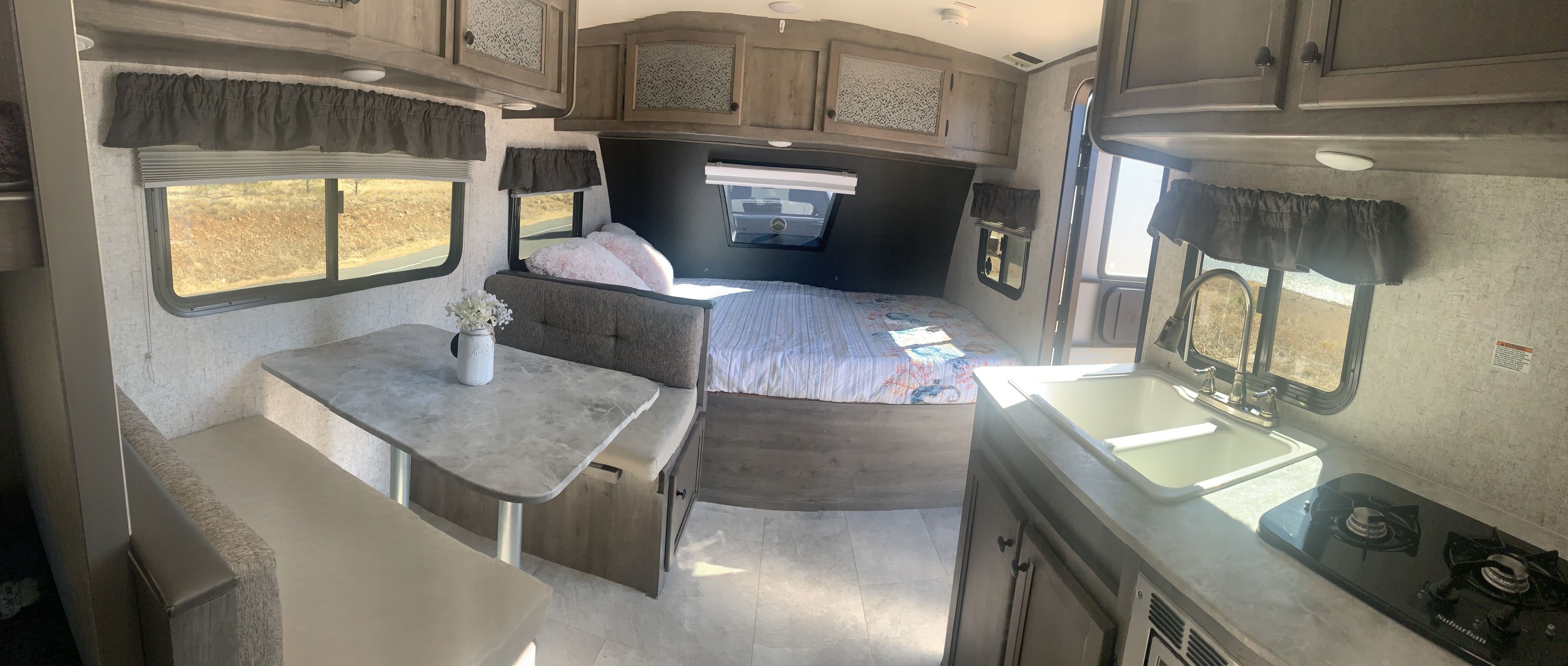 RV rental interior: light-filled space with dinette, compact kitchen, and a comfortable bed.. COACHMEN NANO 2020