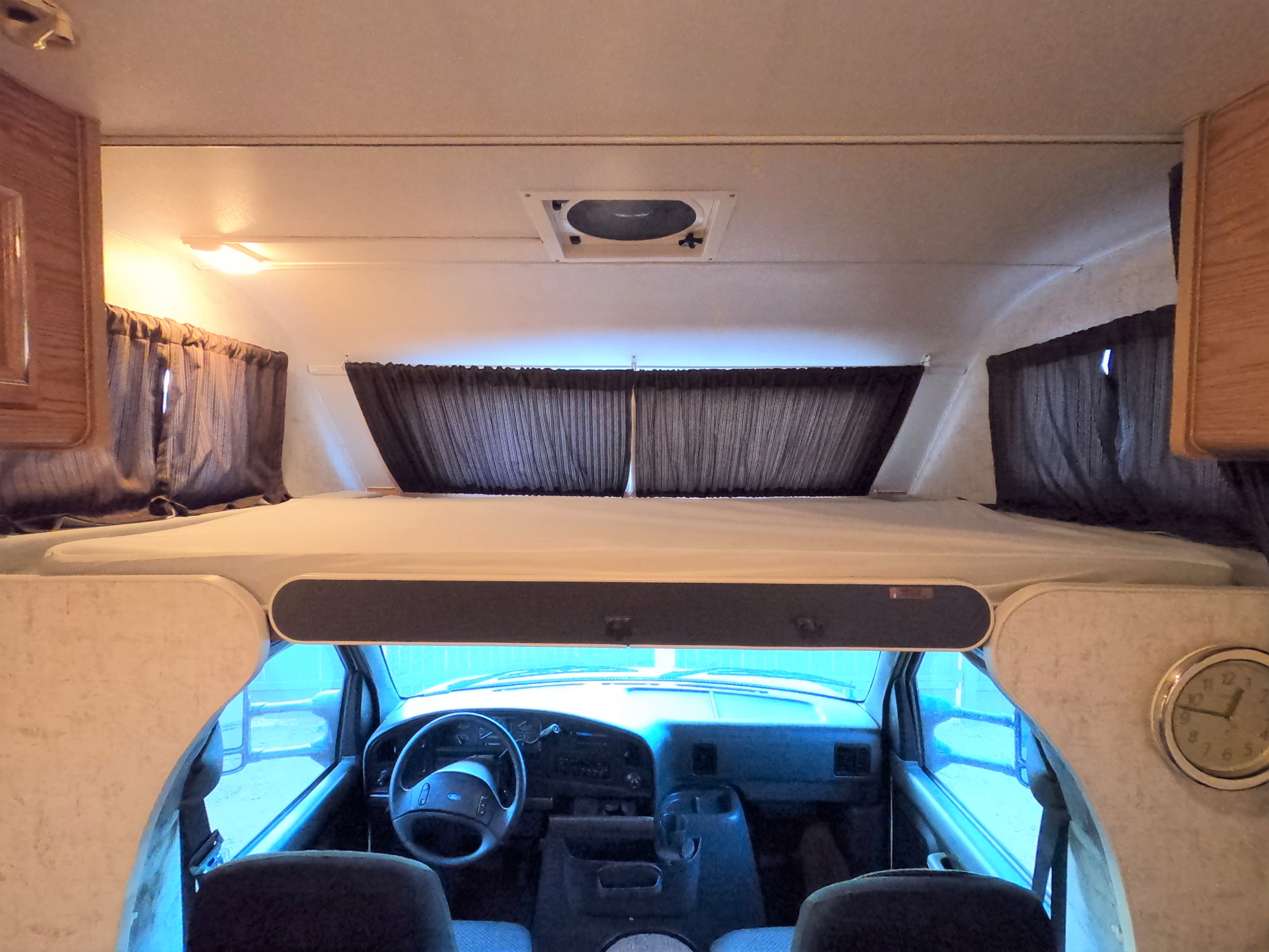 Spacious rv rental interior featuring a cozy cab-over bunk bed and a view of the driver's cockpit. Perfect for travel!. Ford Tioga Montara 1993