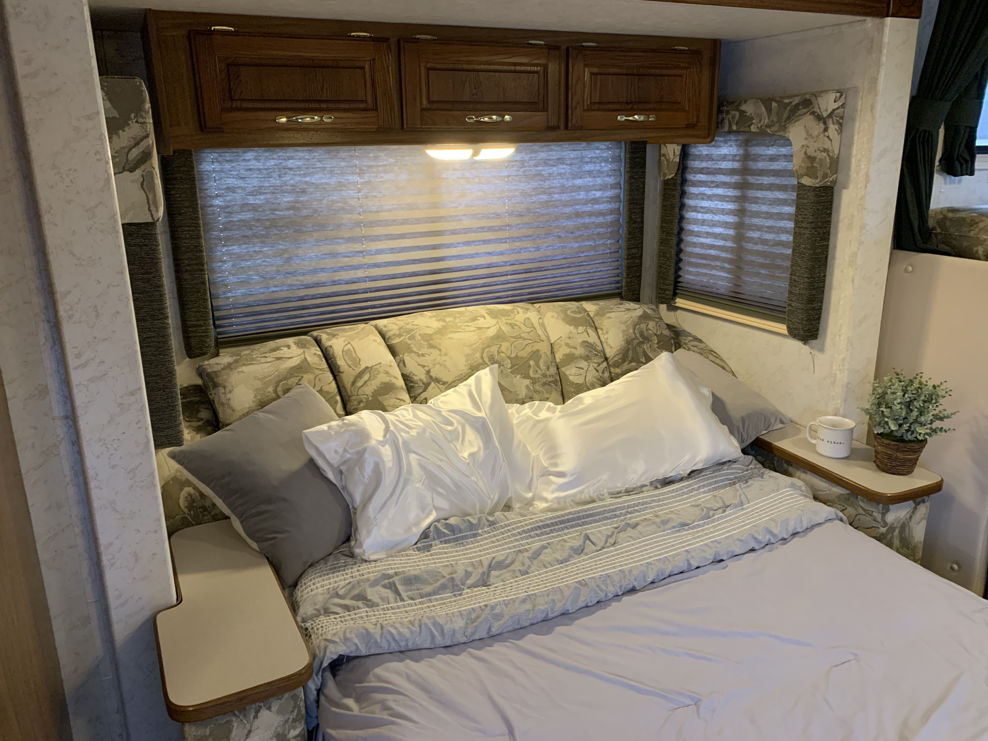 Bedroom view of an RV rental featuring a plush bed, overhead storage, and blinds for privacy.. Thor Motor Coach Chateau 2001