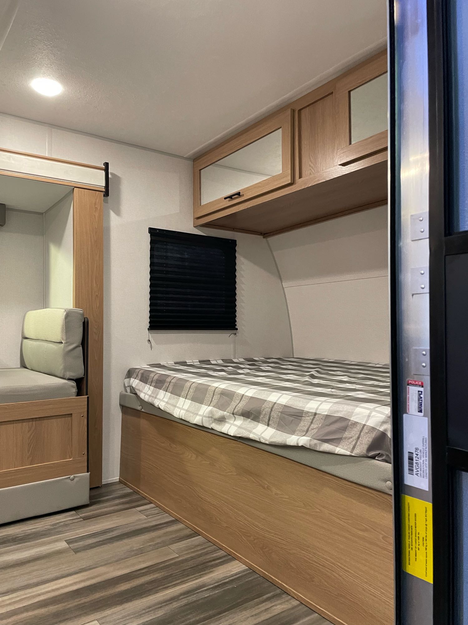 Explore this modern RV rental interior featuring a comfortable bed, overhead cabinets, and compact seating area.. Forest River 17Ft 2022