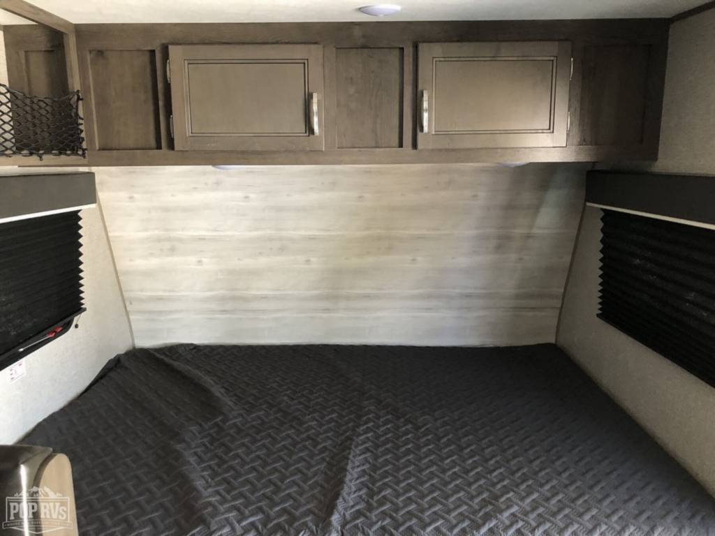 RV rental bedroom: Features a comfy dark grey bed, overhead storage cabinets, and light wood accent walls. Ideal for travel.. Jayco Jay Flight 2021