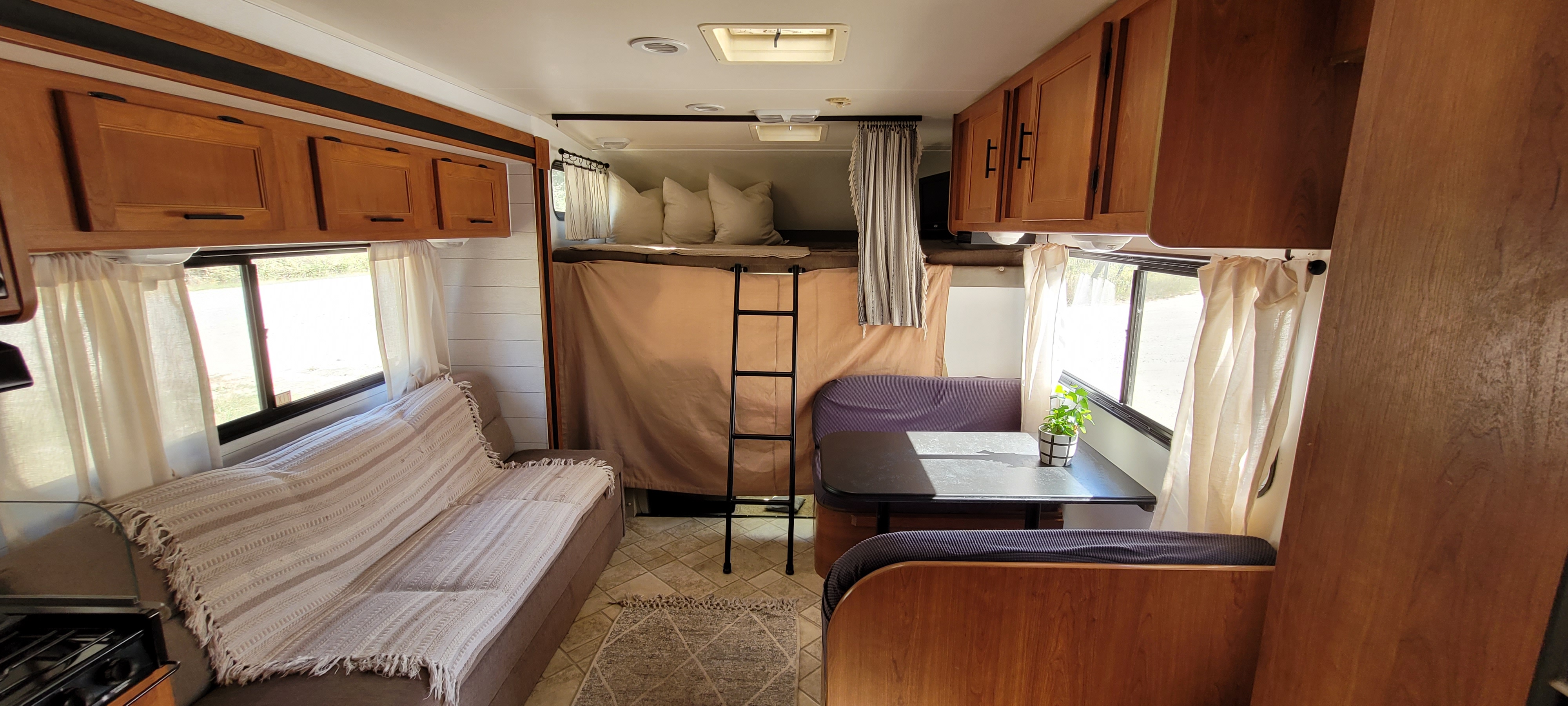 Inviting RV rental interior: wood cabinets, comfortable sofa, overhead bunk, and dinette create a cozy living space.. Other Freelander 2011