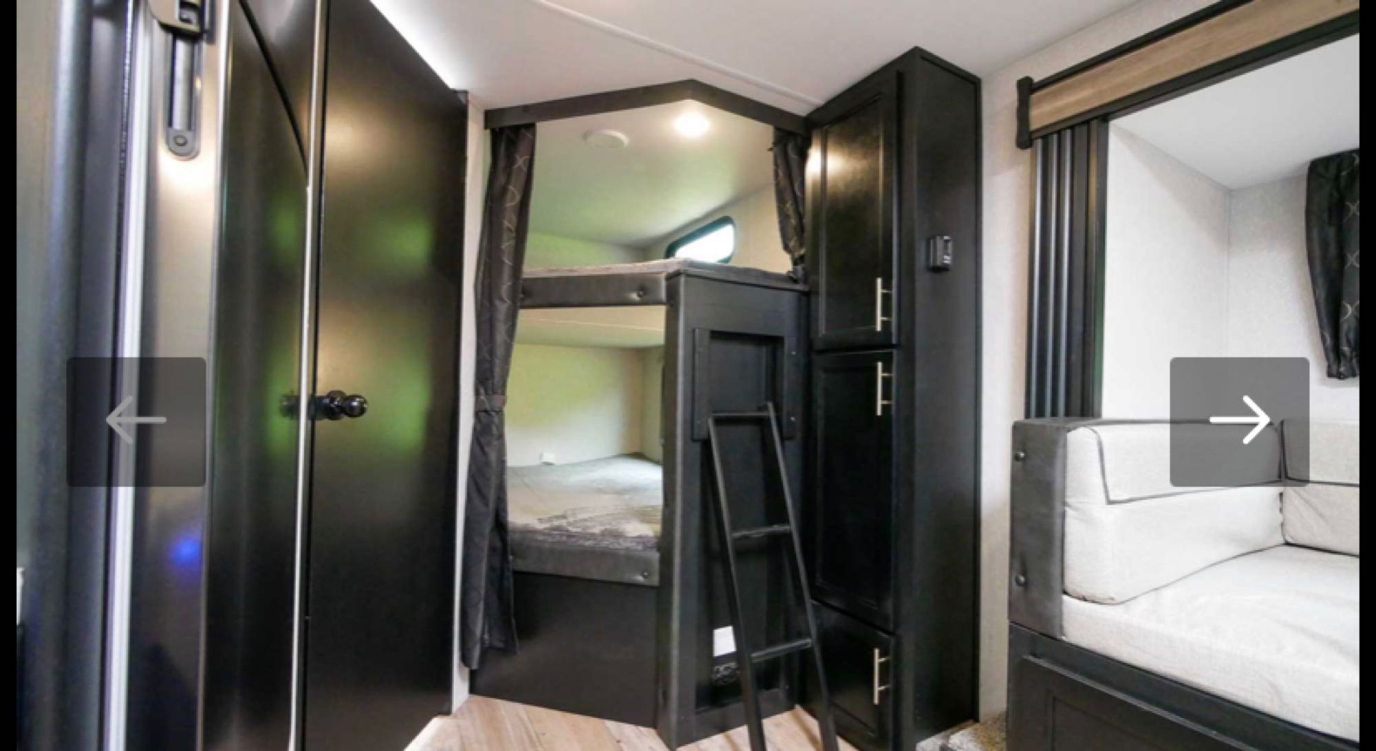 This RV rental interior features dark cabinetry, built-in bunk beds with a ladder, and a cozy sofa area. Ideal for travel.. Forest River Cherokee Grey Wolf 2021