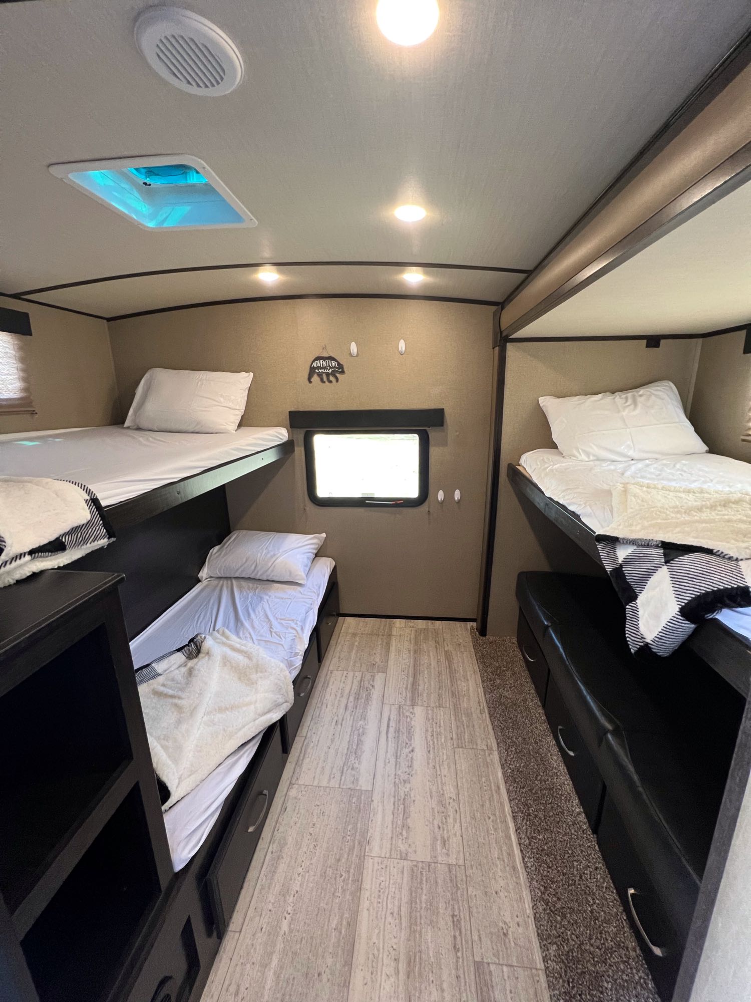 Inside an RV rental bunkhouse: multi-level beds with bedding, storage shelves, and a window. Perfect for a family road trip.. Grand Design Imagine 2018