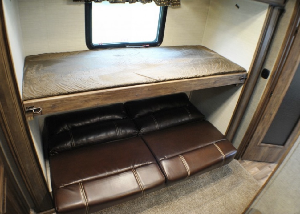 RV rental bunk bed setup with a cozy mattress over a dark leather convertible sofa/futon, perfect for family adventures.. Keystone RV Cougar 2019