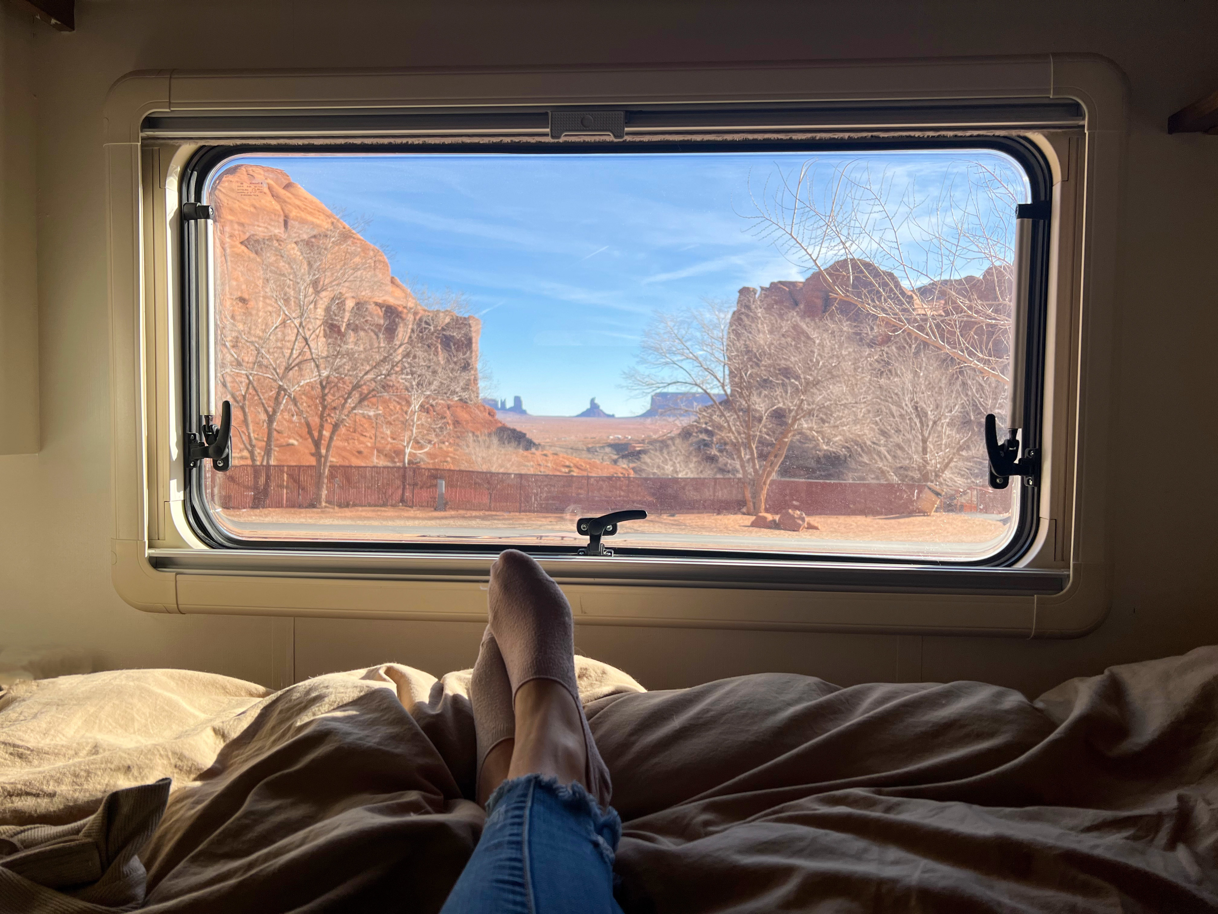 Relaxing in an RV rental, feet up on the bed, with a stunning Monument Valley desert view from the window.. Winnebago View 2016