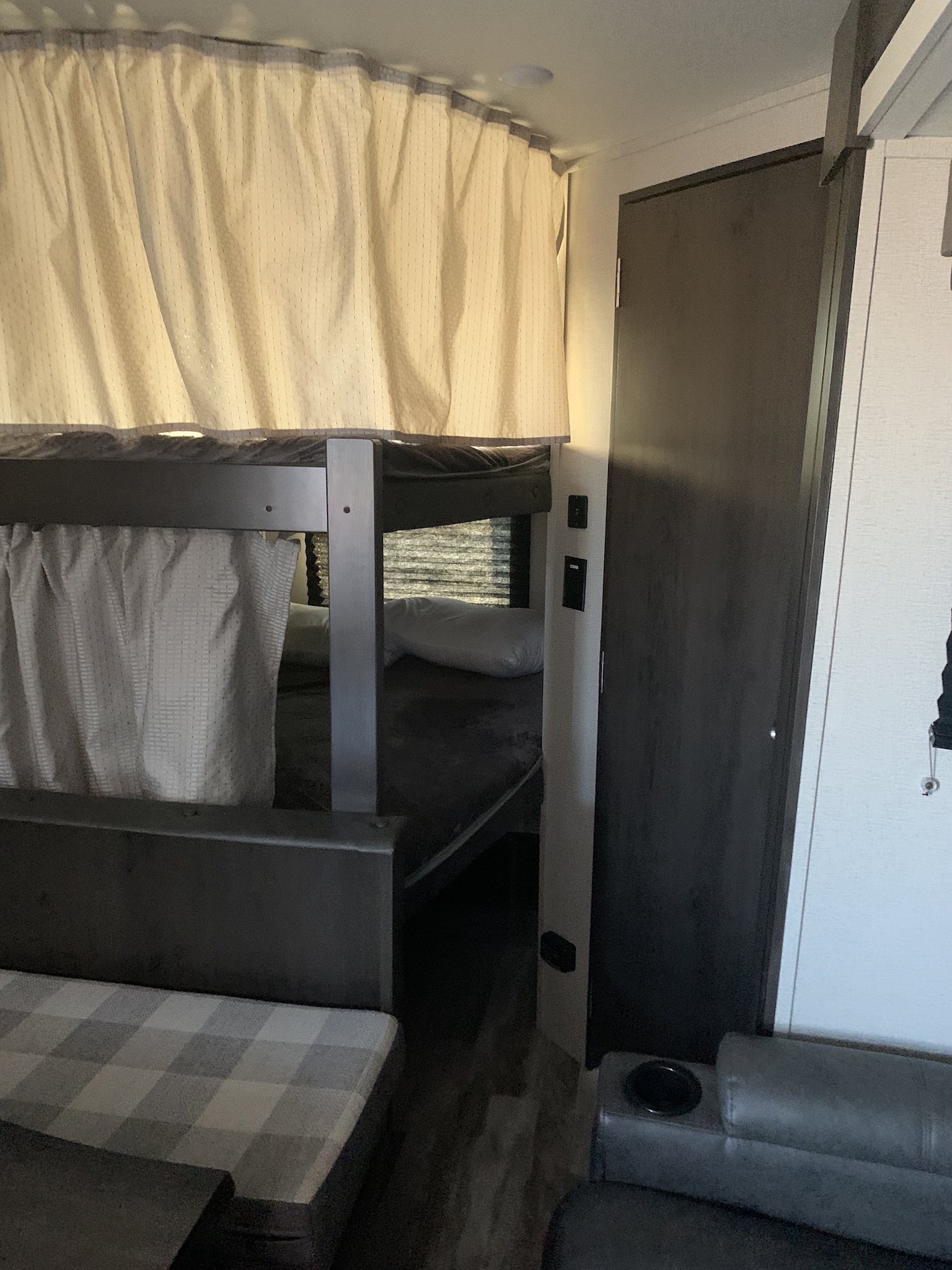 RV rental interior featuring bunk beds with privacy curtains, a checkered dinette, and a comfy lounge area.. Grand Design Transcend Xplor 2020