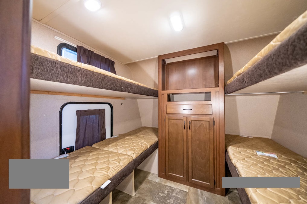 RV rental interior showcasing multiple bunk beds and a central storage unit, optimizing sleeping space for travelers.. Jayco Jay Feather Ultra Lite 2015