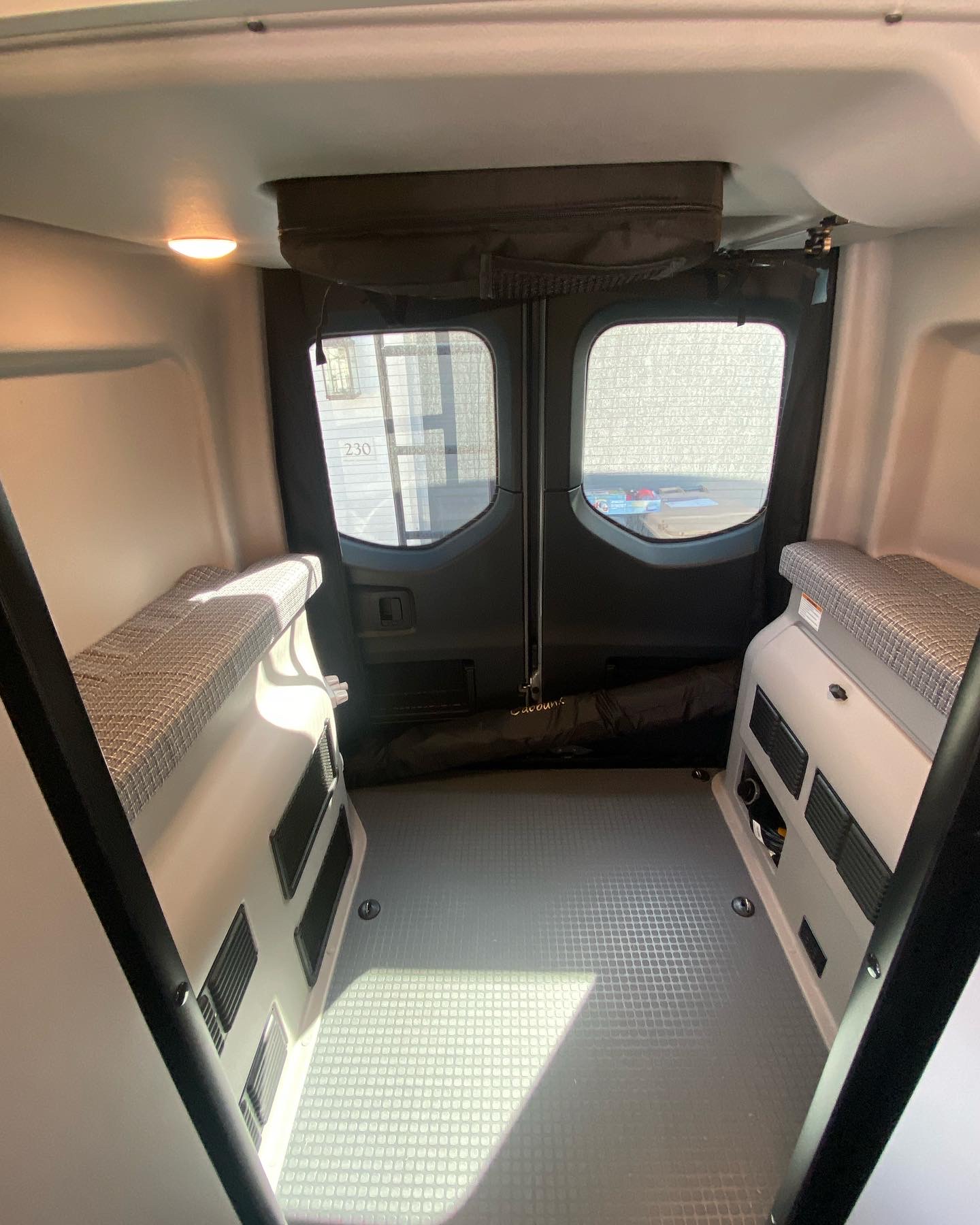 Inside an RV rental: versatile interior with patterned bench seating, durable floor, and rear windows.. Winnebago Revel 2022