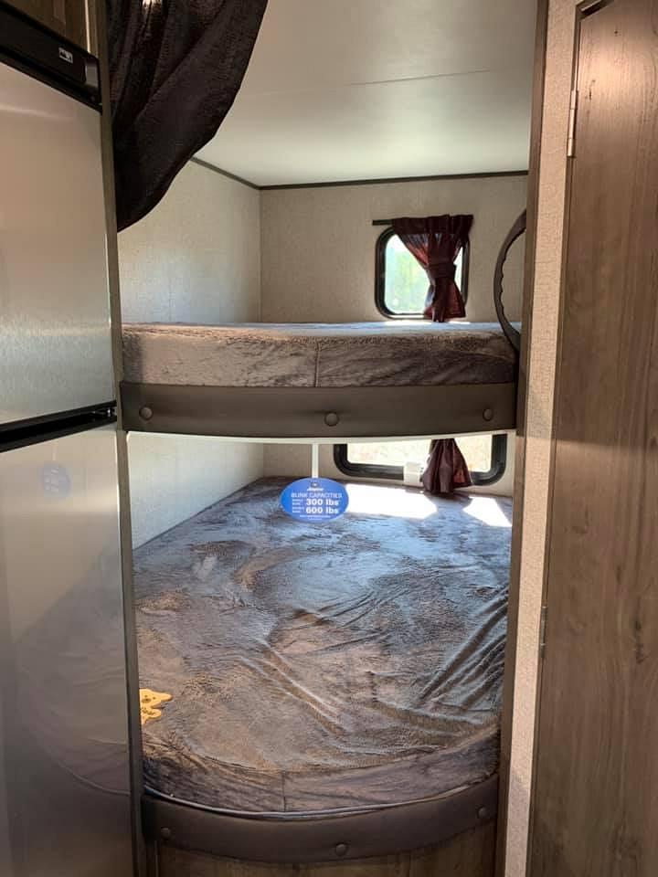 Inside an RV rental: two compact bunks with windows & curtains, ideal for extra sleeping space on trips.. Jayco Jay Flight 2021