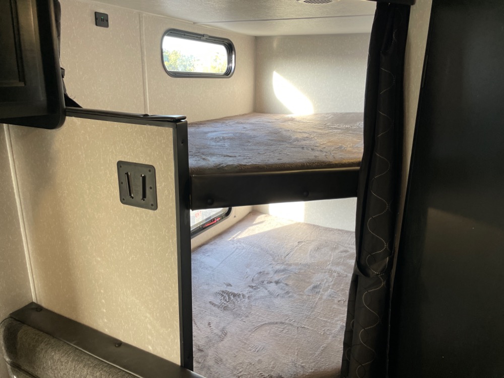 RV rental bunk beds offering a compact sleeping area. Features include two bunks, a window, and wall mounts.. Forest River Grey Wolf 26DJSE 2022