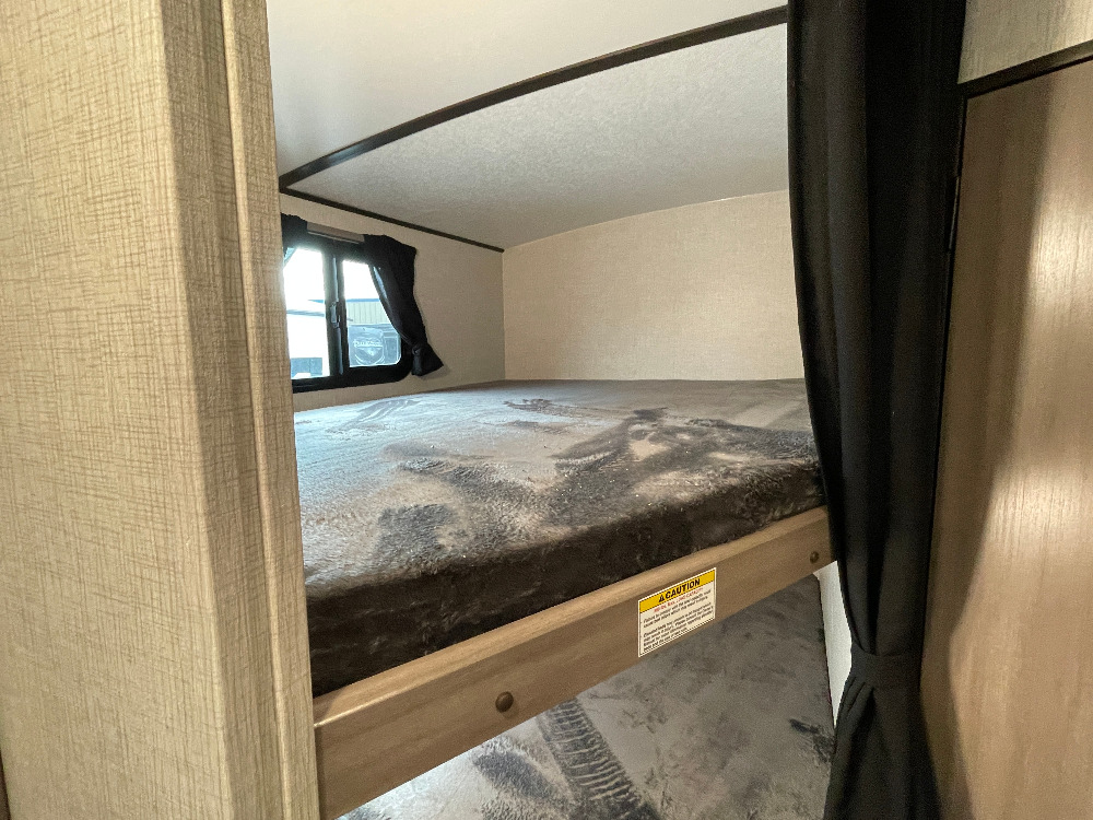 Inside an RV rental: view of bunk beds with a soft mattress and window, offering a cozy sleeping space for your next trip.. Crossroads Sunset trail 242HB 2022