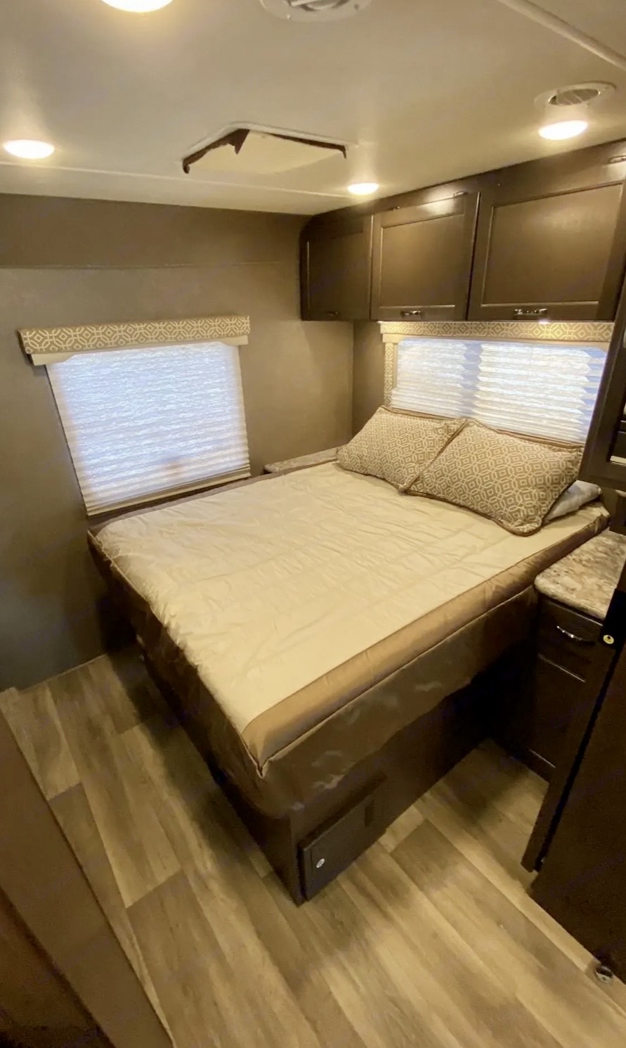 RV rental bedroom: a cozy bed, overhead cabinets, and windows with privacy blinds for comfortable travel.. Thor Motor Coach Freedom Elite 2019
