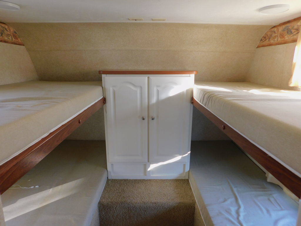 Spacious RV rental interior featuring two sets of comfortable bunk beds and a useful central cabinet.. Keystone RV Outback 2007