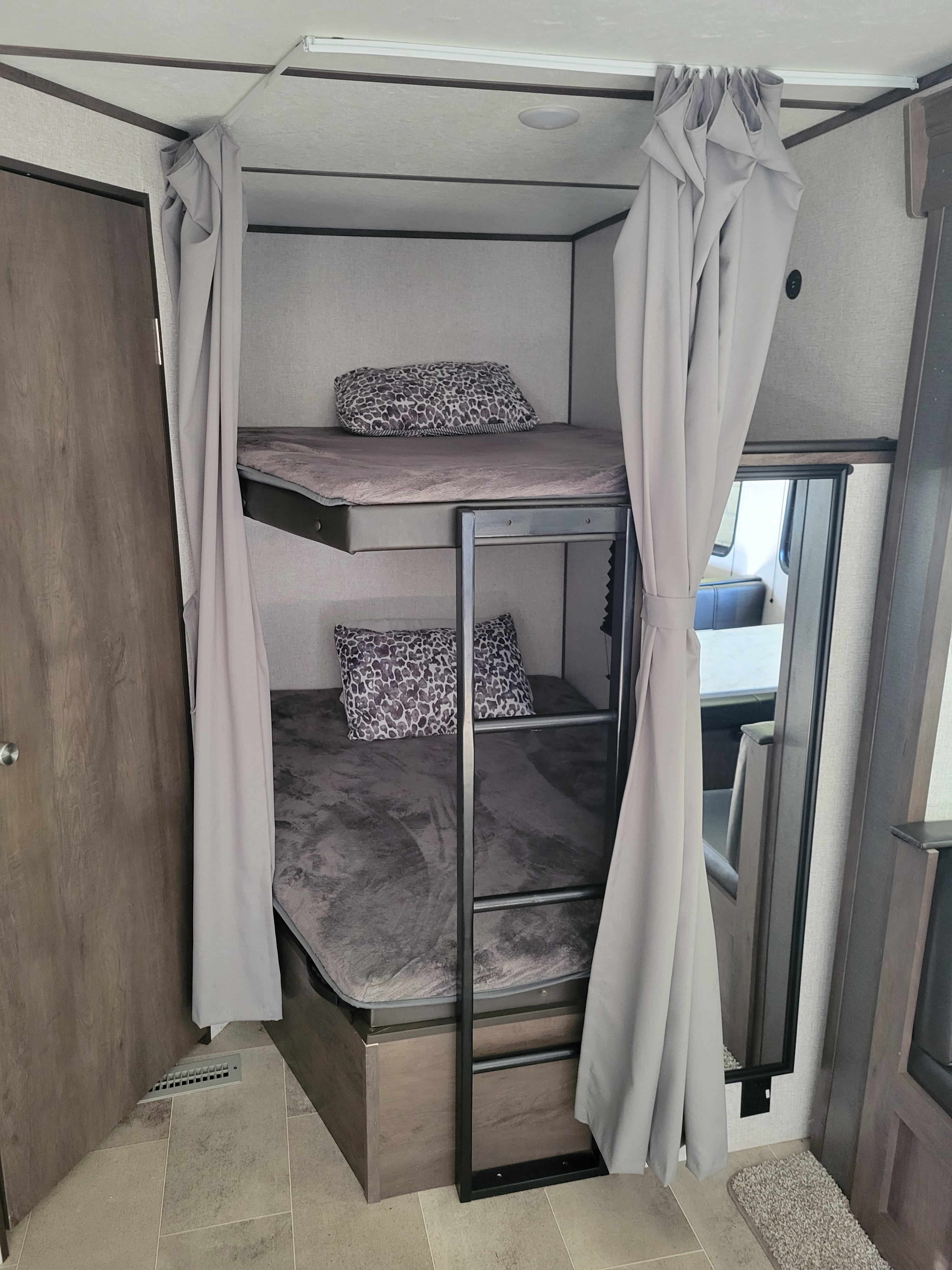 An RV rental's double bunk beds with plush bedding and privacy curtains for a comfortable, compact sleeping area.. Coleman 263 BH Lantern Edition 2021