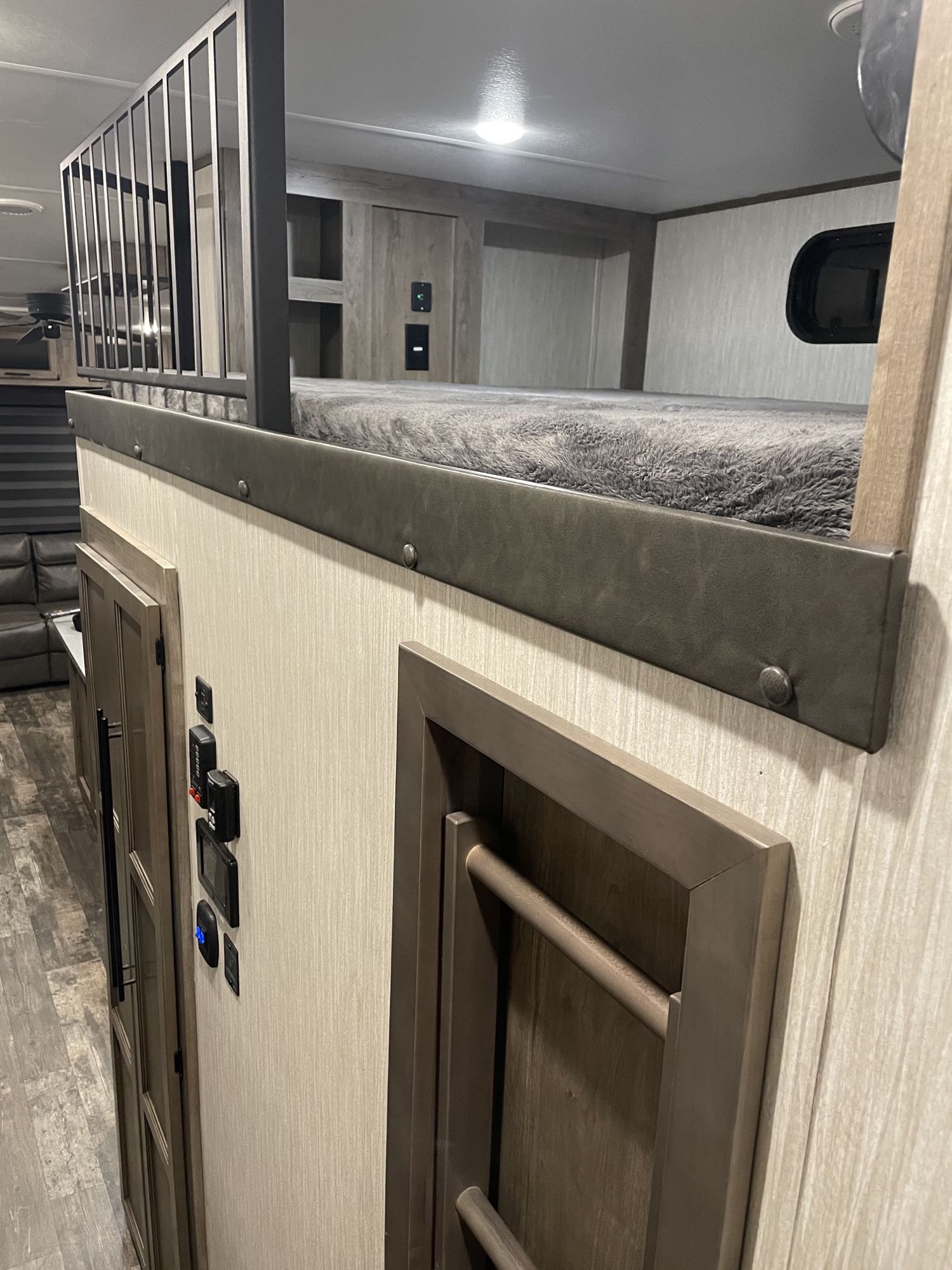 Modern rv rental interior showing a cozy bunk bed with metal railing, wall controls, and textured wall finish.. Forest River Sabre 2021