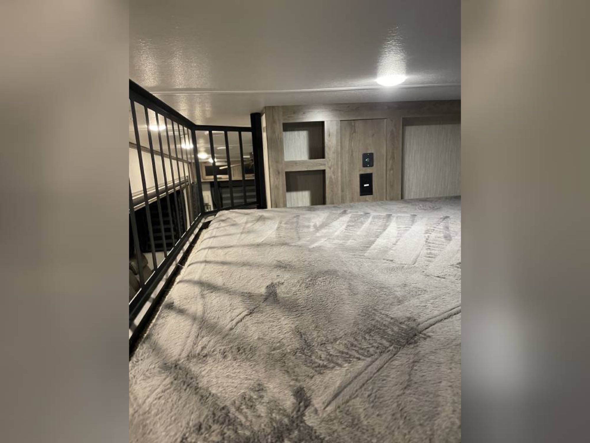 Plush gray blanket on an RV rental bunk bed. Modern interior with built-in shelves & outlets for your comfort.. Forest River Sabre 2021