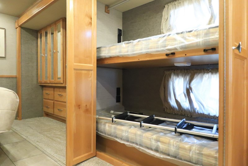 RV rental: Interior with bunk beds (ladder on bottom, plastic-covered mattresses) and a wooden wardrobe with mirrored doors.. Allegro Allegro Open Road 2022