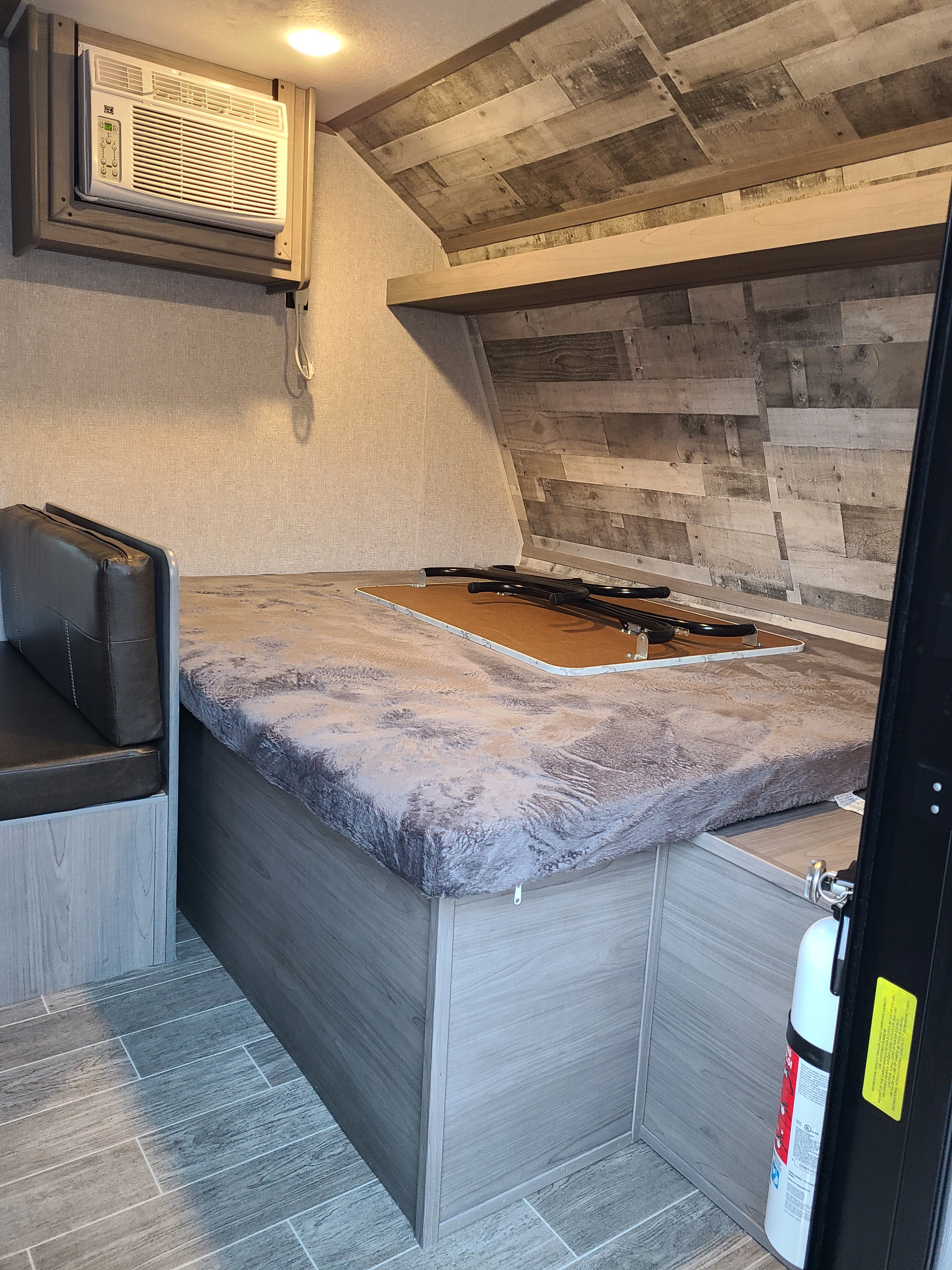 Cozy RV rental interior with a bed/lounge area, dinette seating, AC unit, and fire extinguisher. Ready for adventure!. Coleman Latern 17b 2022