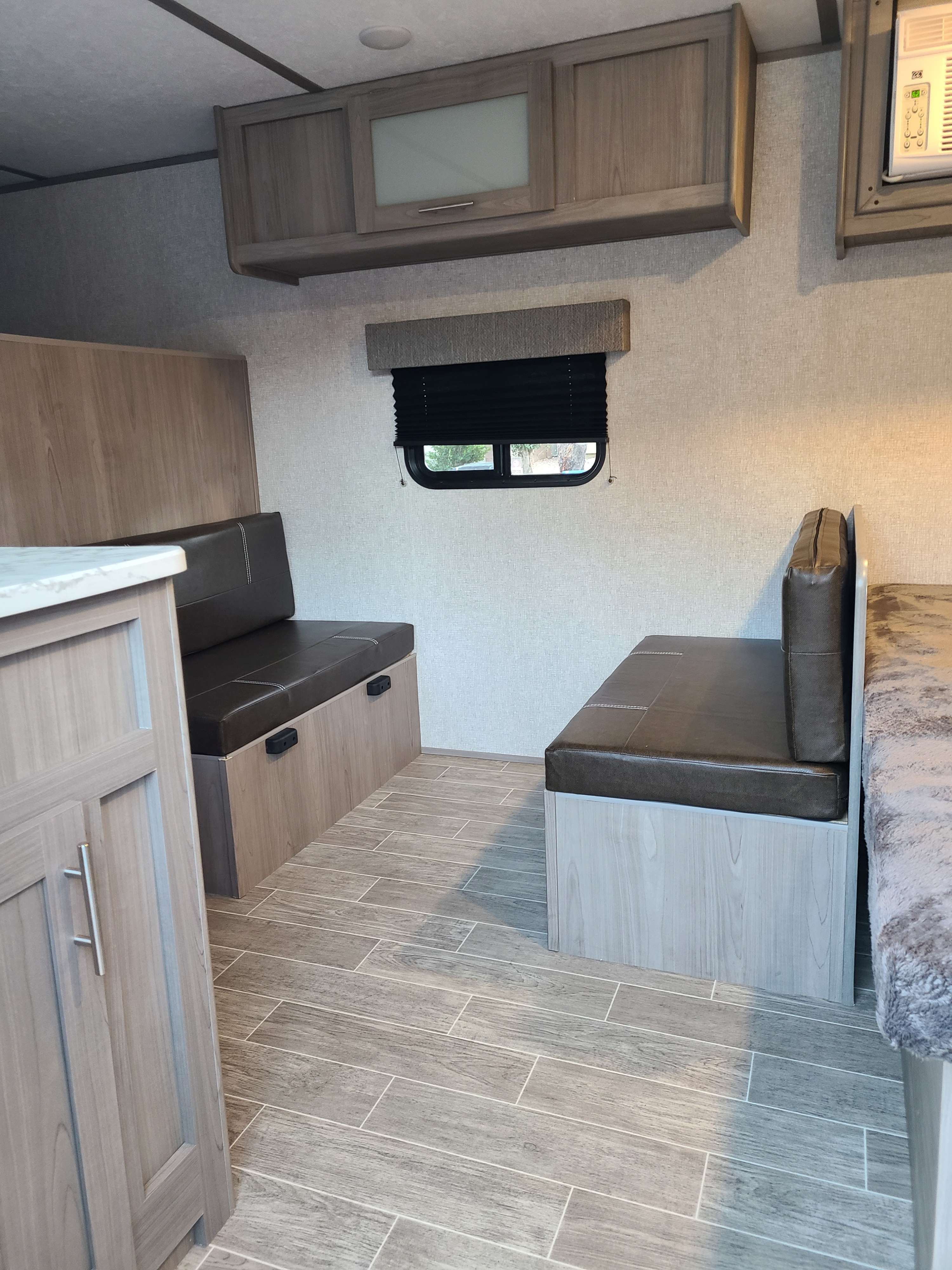 RV rental interior: modern dinette with comfy benches, light wood cabinets, window, AC unit, and stylish tiled floor.. Coleman Latern 17b 2022