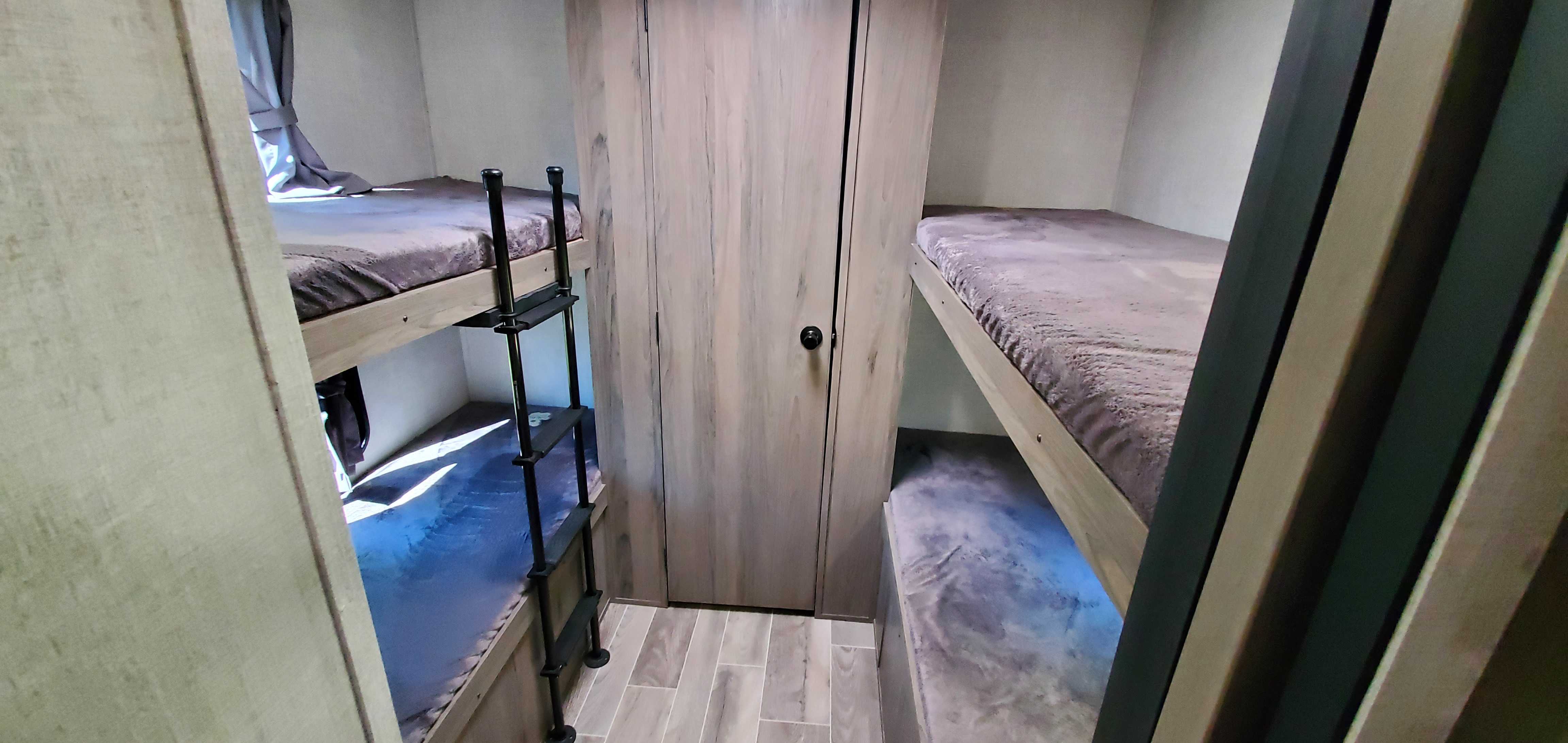 This cozy rv rental bunk area features multiple beds, a ladder, and built-in wardrobe, optimizing compact space.. Gulf Stream Trailmaster 2021