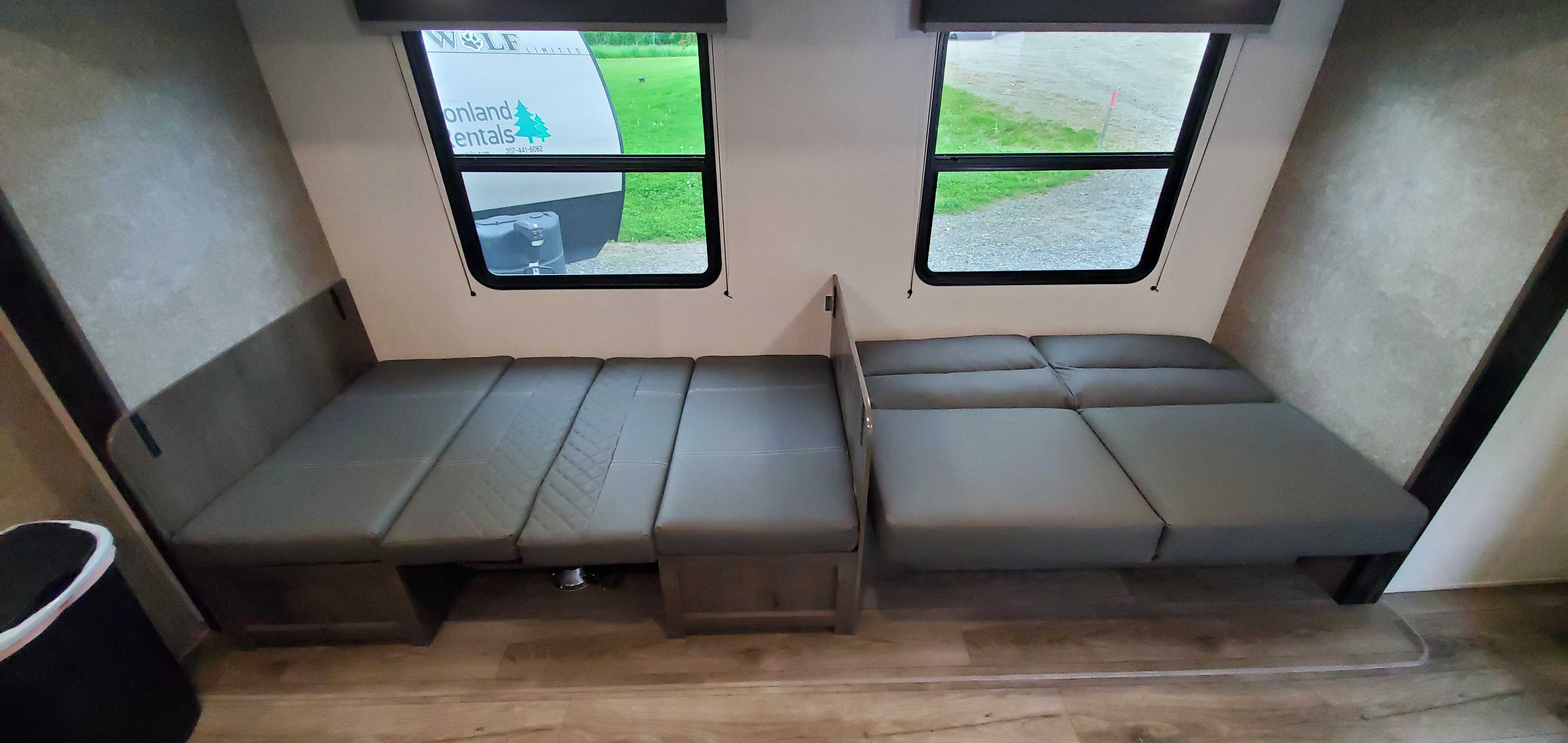 RV rental interior with versatile gray convertible seating and beds. Two windows offer views of the outdoors.. Starcraft Autumn Ridge 2021