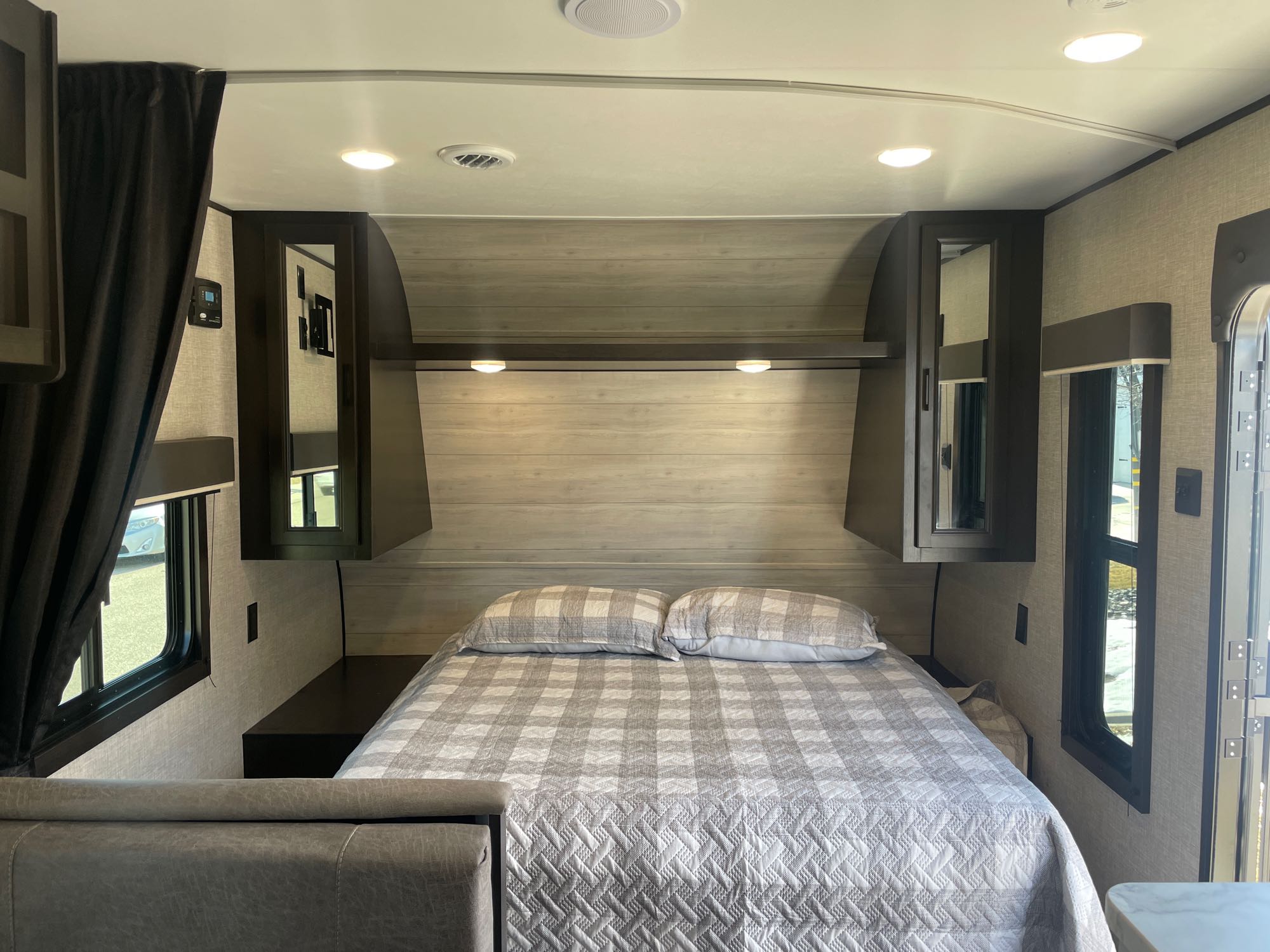 RV rental bedroom featuring a clean gray plaid bed, mirrored cabinets, and side windows for light.. Other Other 2022
