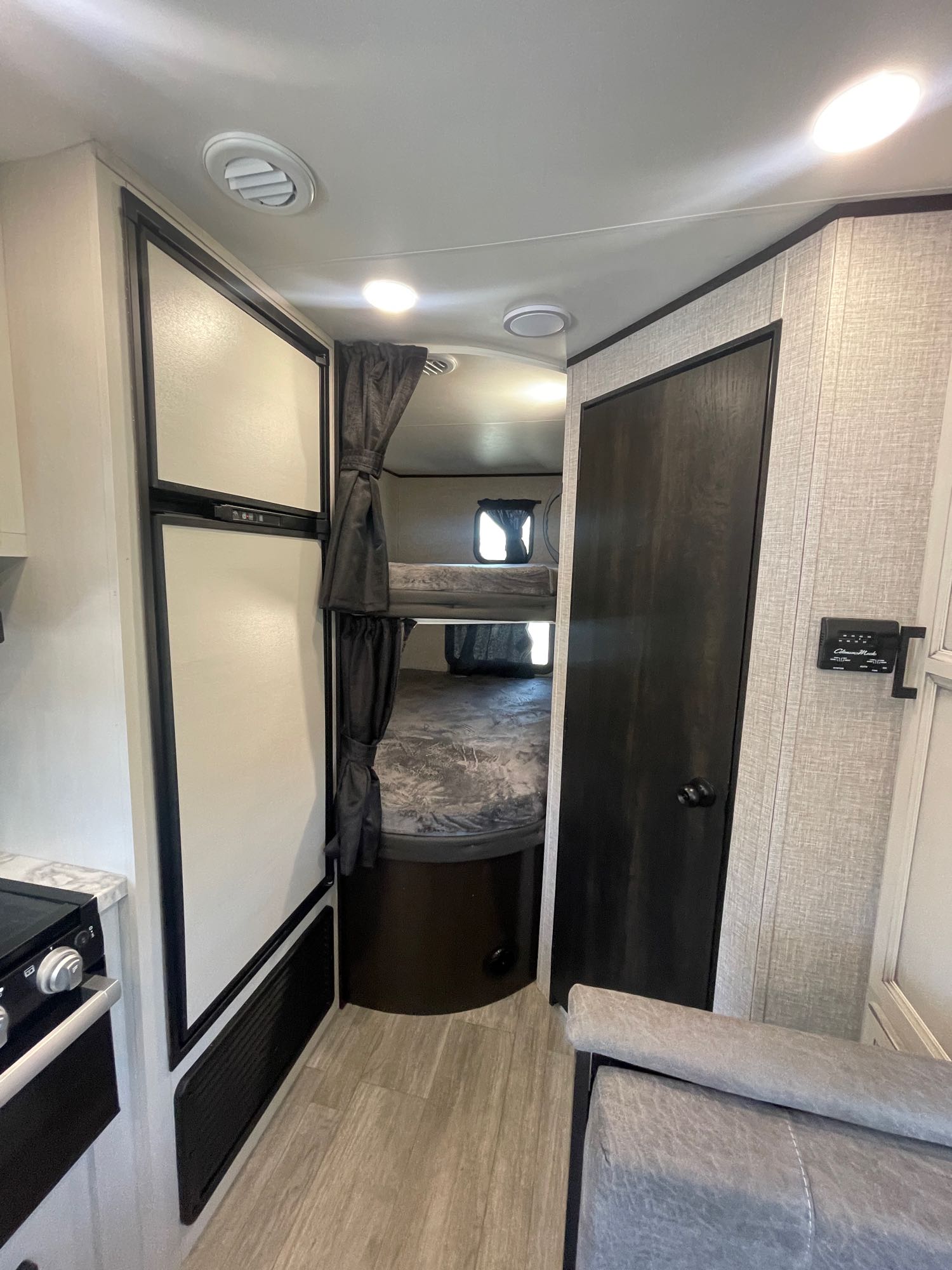 Inside an RV rental: features bunk beds with privacy curtains, a kitchen area with fridge, and a main control panel on the wall.. Other Other 2022