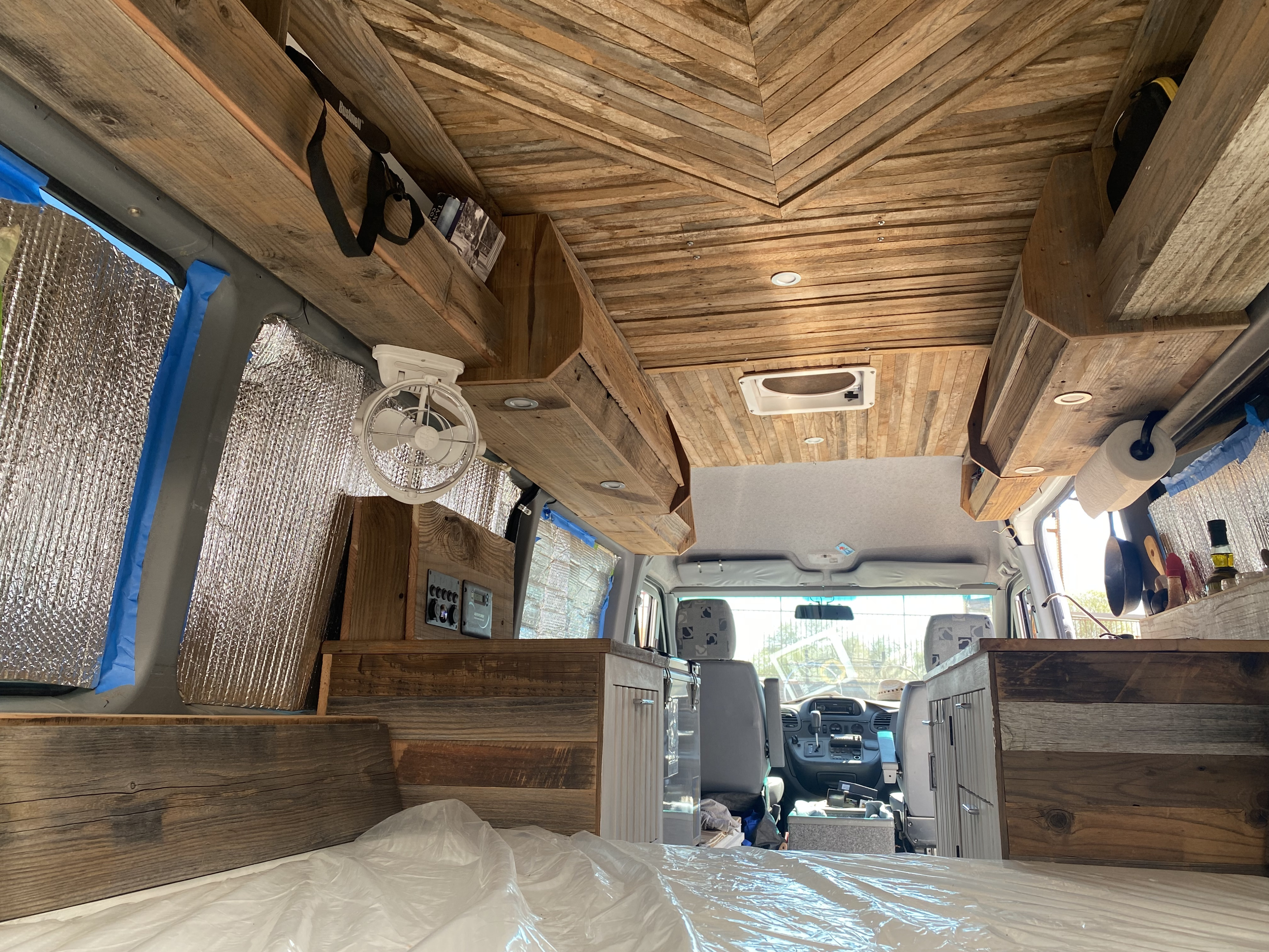 Cozy camper van RV rental interior with custom wooden ceiling, overhead storage, insulated walls, and a bed.. Freightliner Sprinter 2006