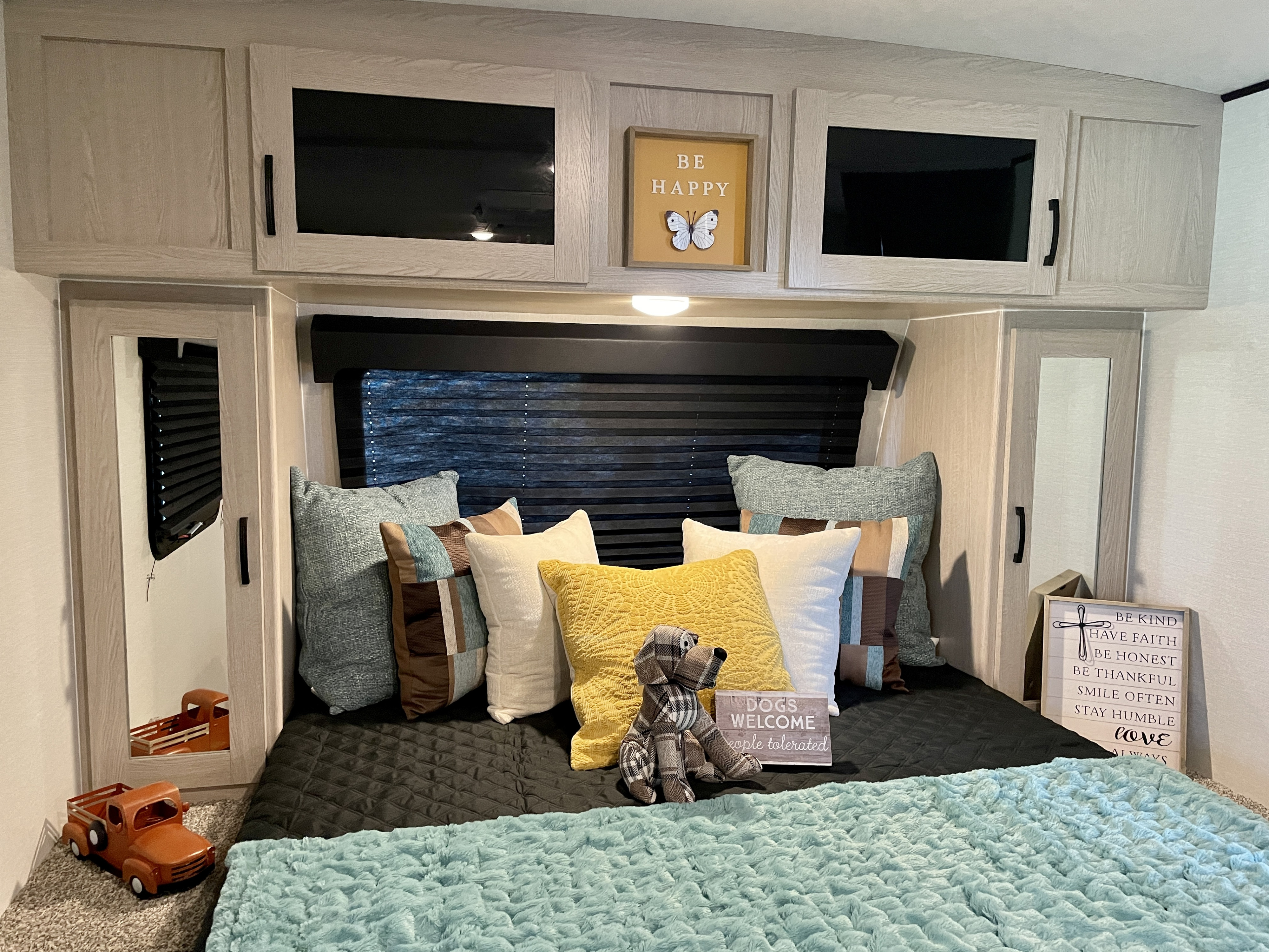 Experience comfort in this RV rental's cozy bedroom, featuring plush bedding, dog decor, and cheerful signs.. Coachmen Apex Nano 2022