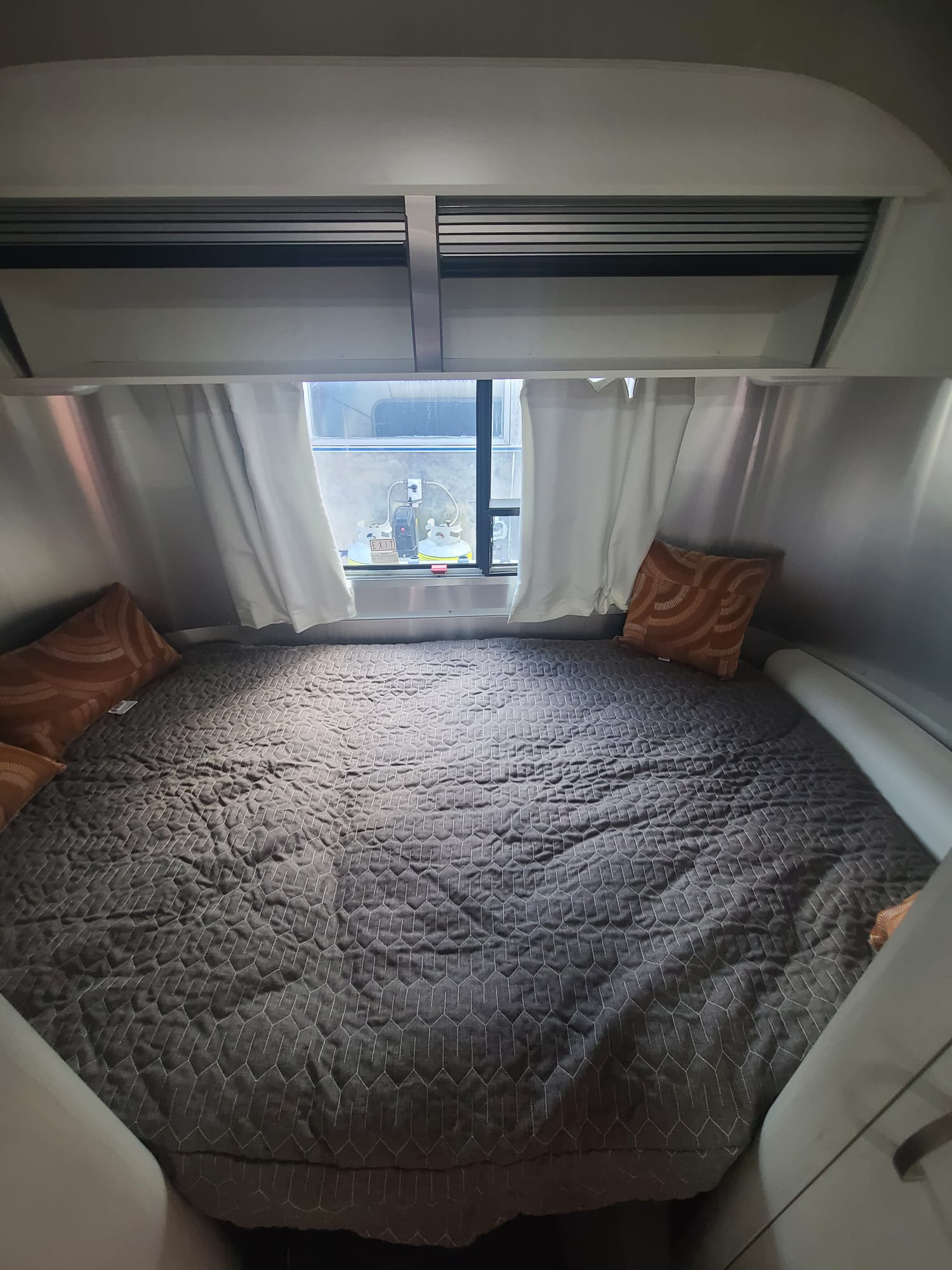 Spacious RV rental bed with modern grey quilt and accent pillows. Perfect for comfortable travel adventures.. Airstream Sport 2017