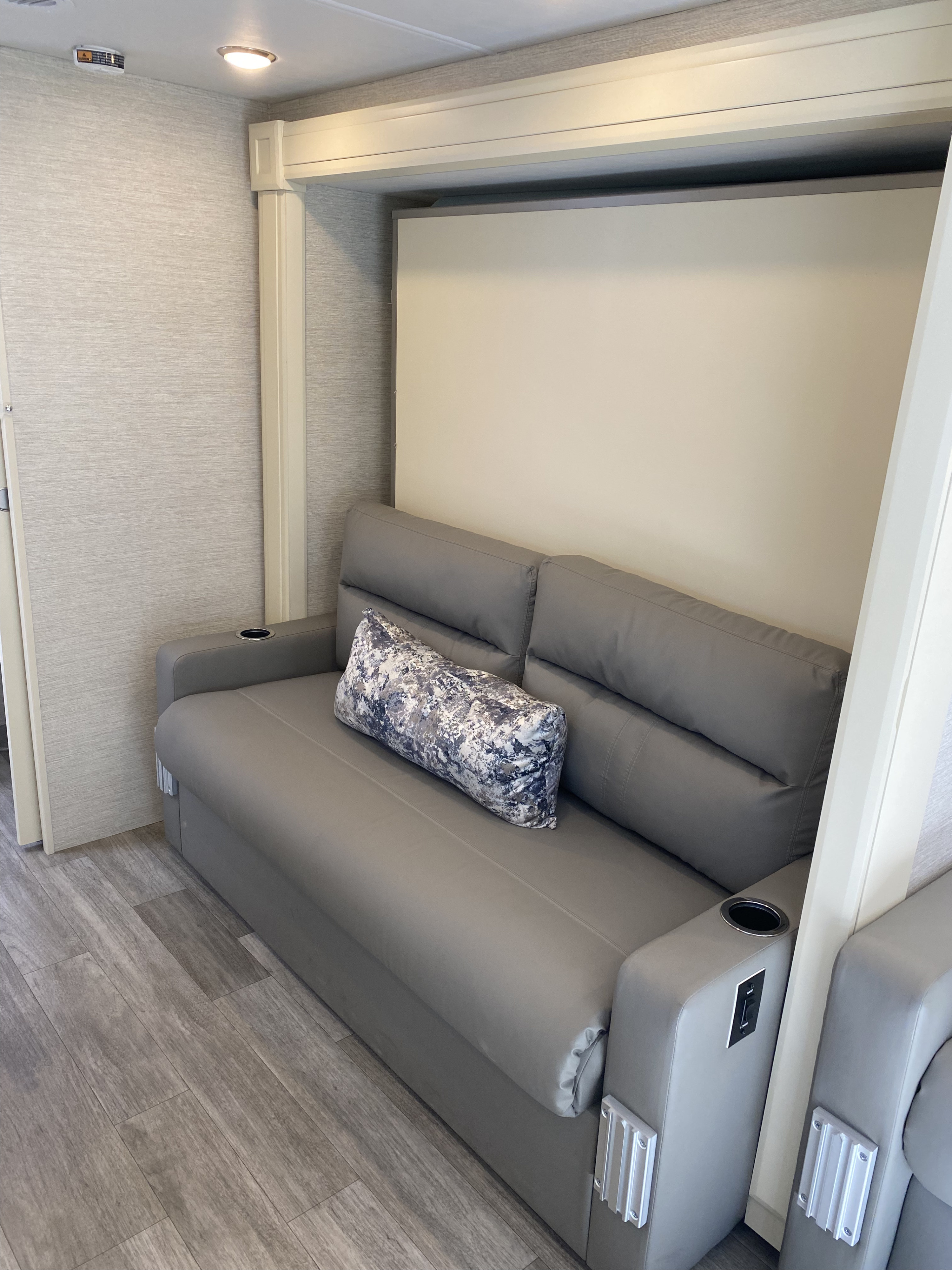RV rental: Modern grey sofa with cup holders, USB ports, and a patterned pillow. This comfortable unit likely converts to a bed.. Tiffin Wayfarer 2022