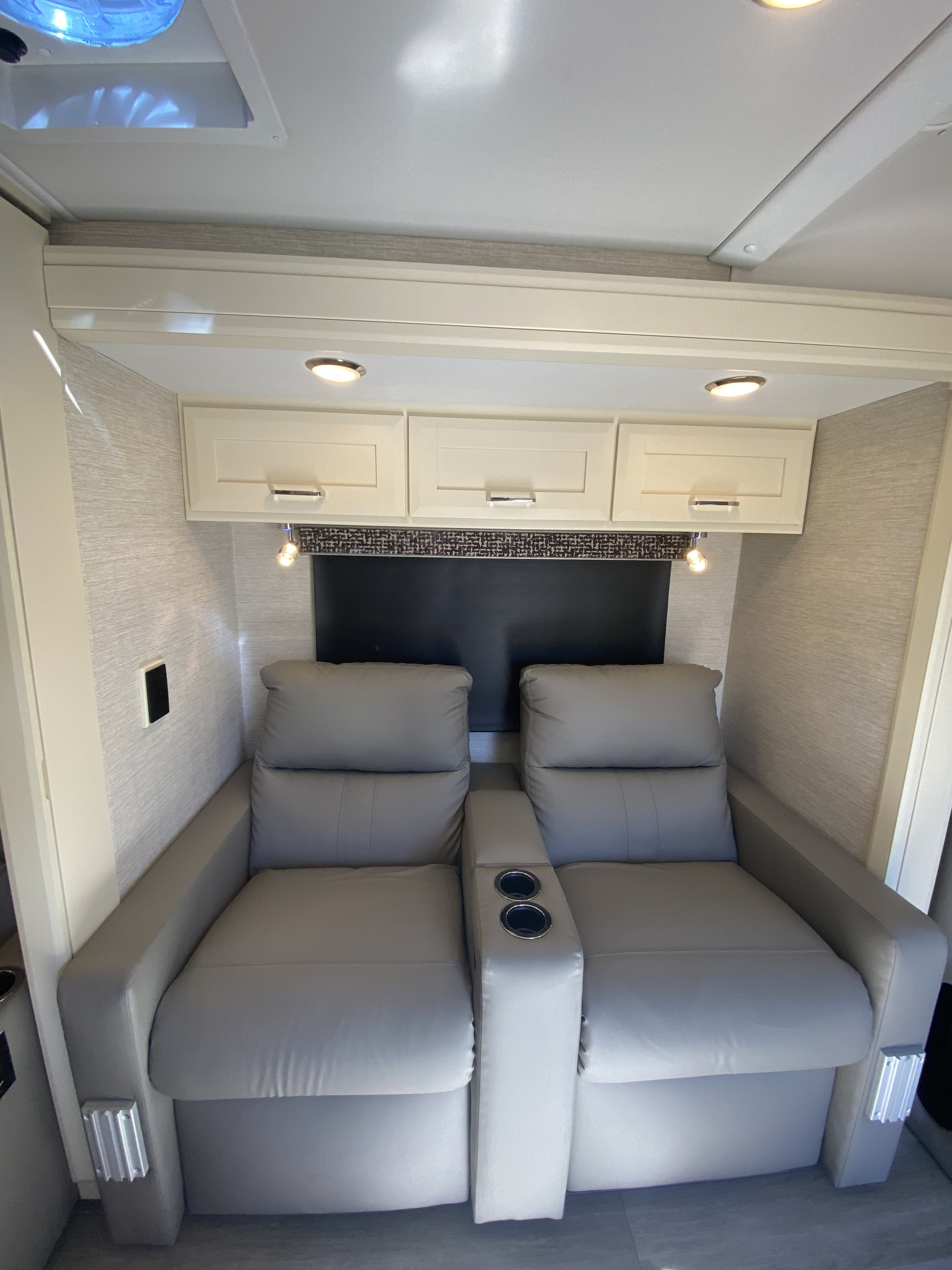 Relax in comfort! This RV rental offers plush gray recliners with cup holders, overhead storage, and accent lighting.. Tiffin Wayfarer 2022