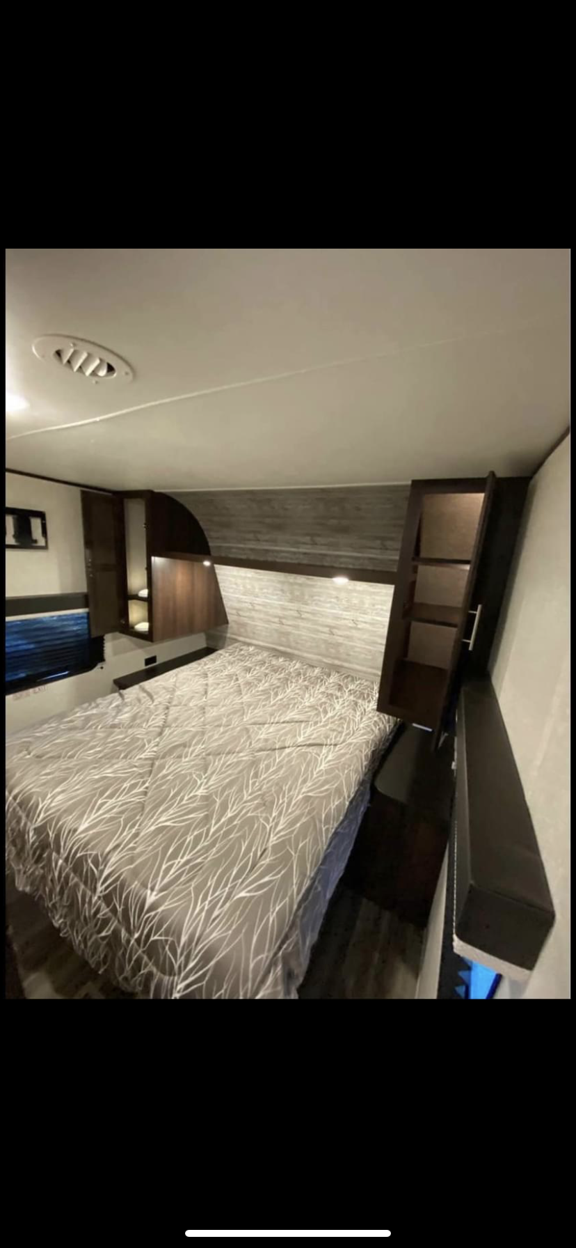 RV rental bedroom: Cozy bed with unique branch-patterned comforter, dark wood storage, and ceiling vent.. Jayco Jay Flight 2019
