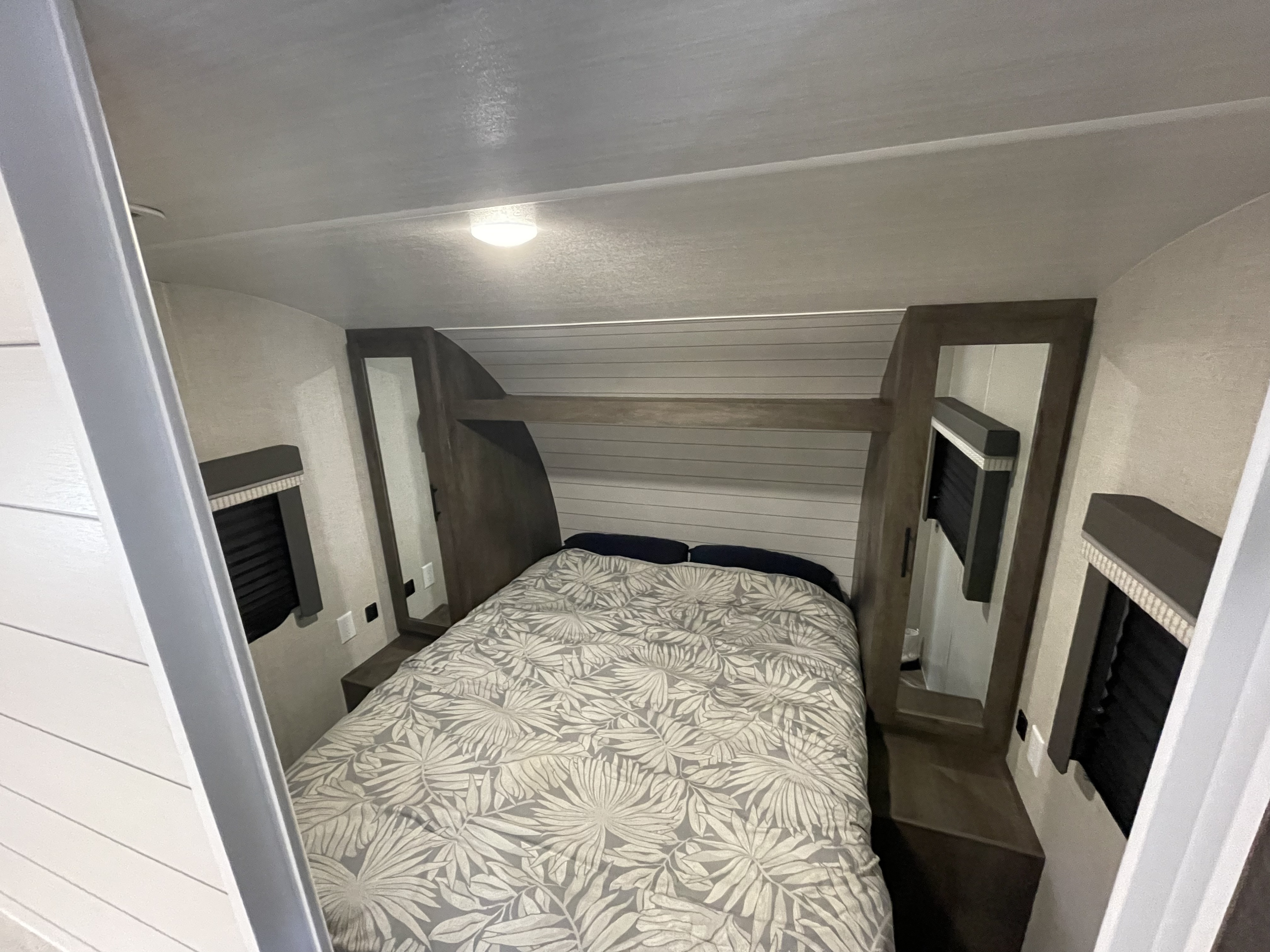 A cozy RV rental bedroom: patterned bed, mirrored storage, windows, and bright overhead lighting for a comfortable journey.. Forest River Salem Cruise Lite 2021