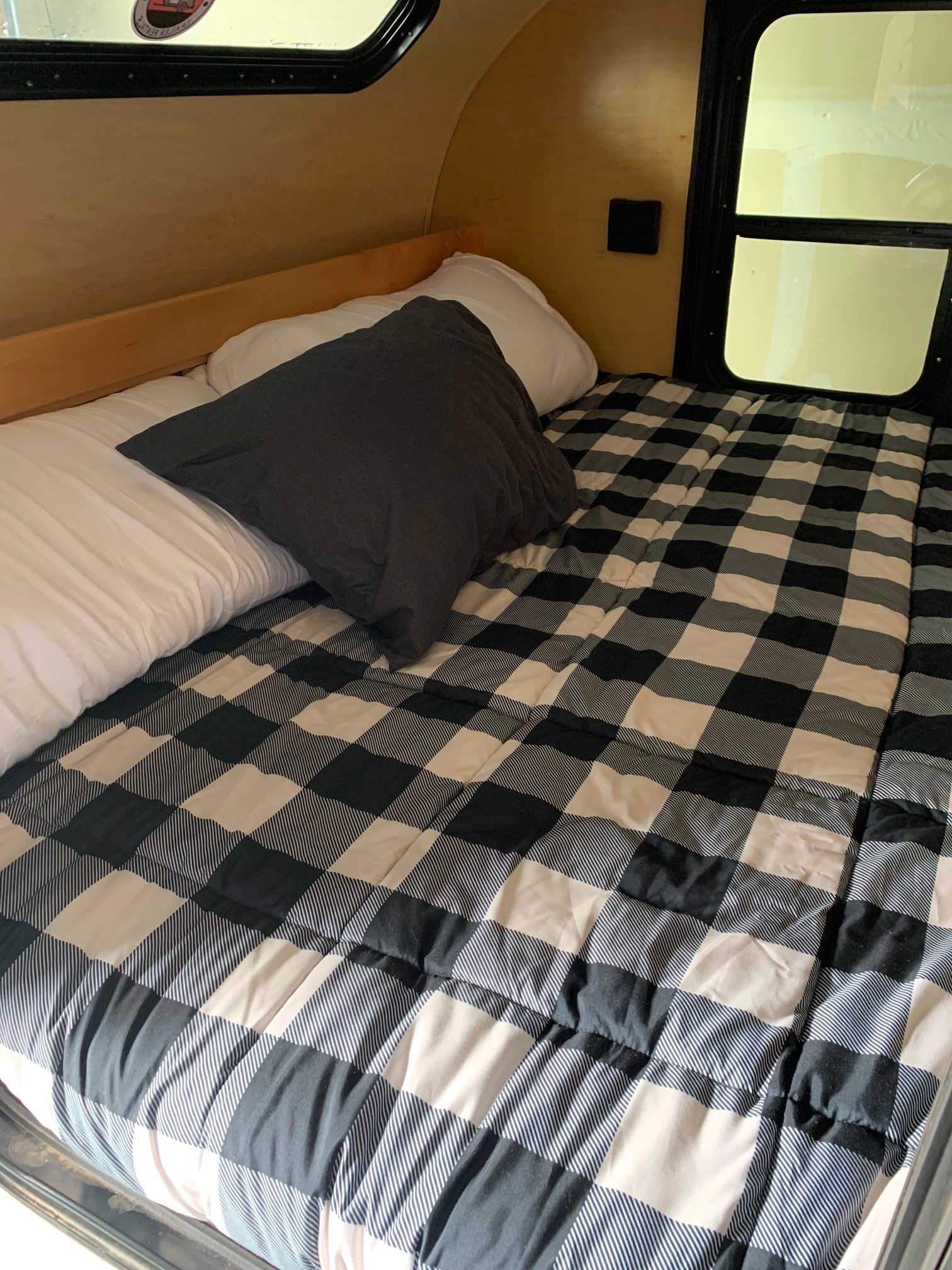Cozy RV rental interior: a comfortable bed with white and dark pillows, covered by a black and white buffalo plaid comforter.. Little Guy Silver Shadow 2015