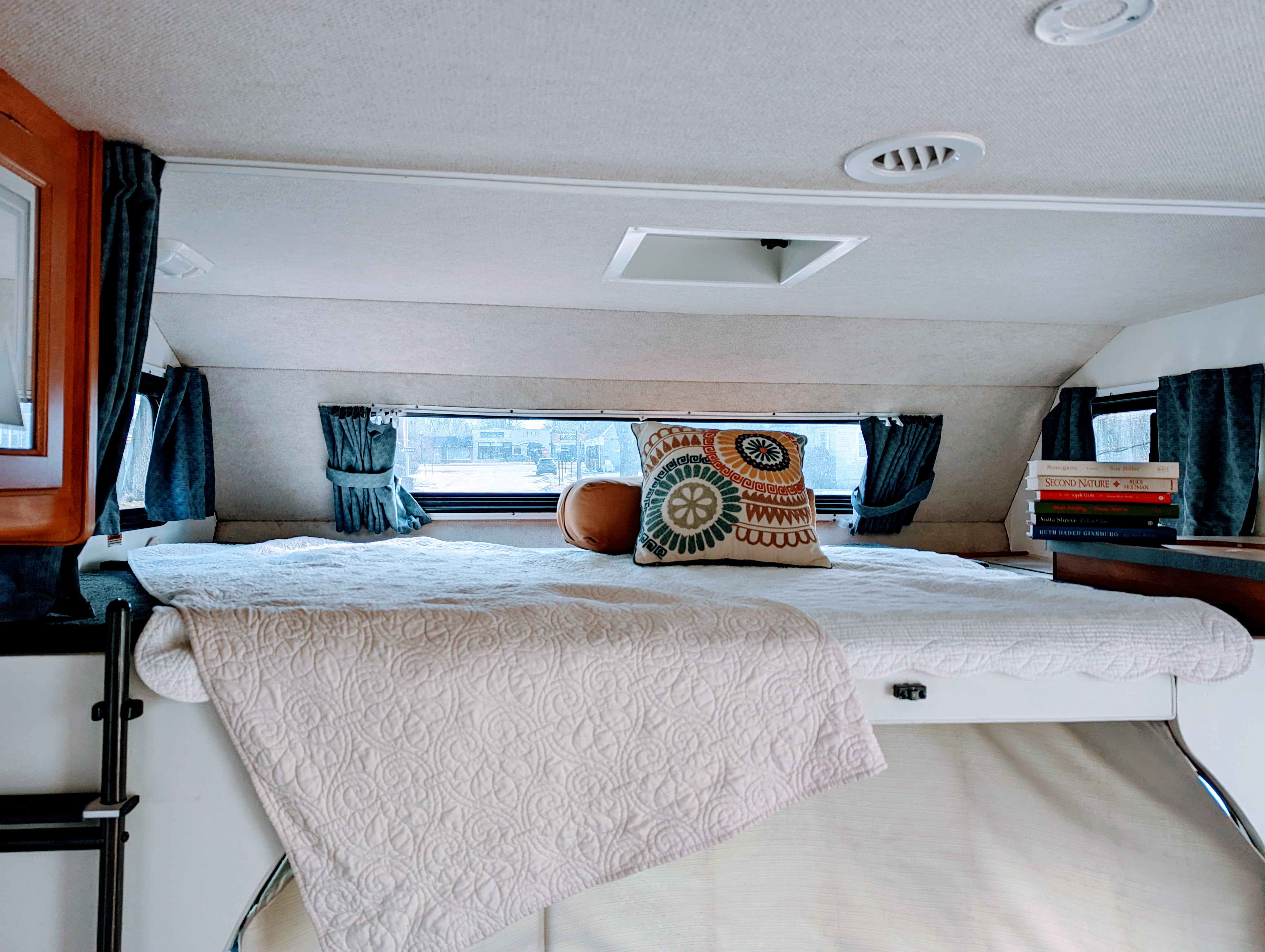 Bright, cozy RV rental bedroom features a large bed with quilted blanket & pillows. Window offers a street view; ideal for travel.. Fleetwood Tioga 2005