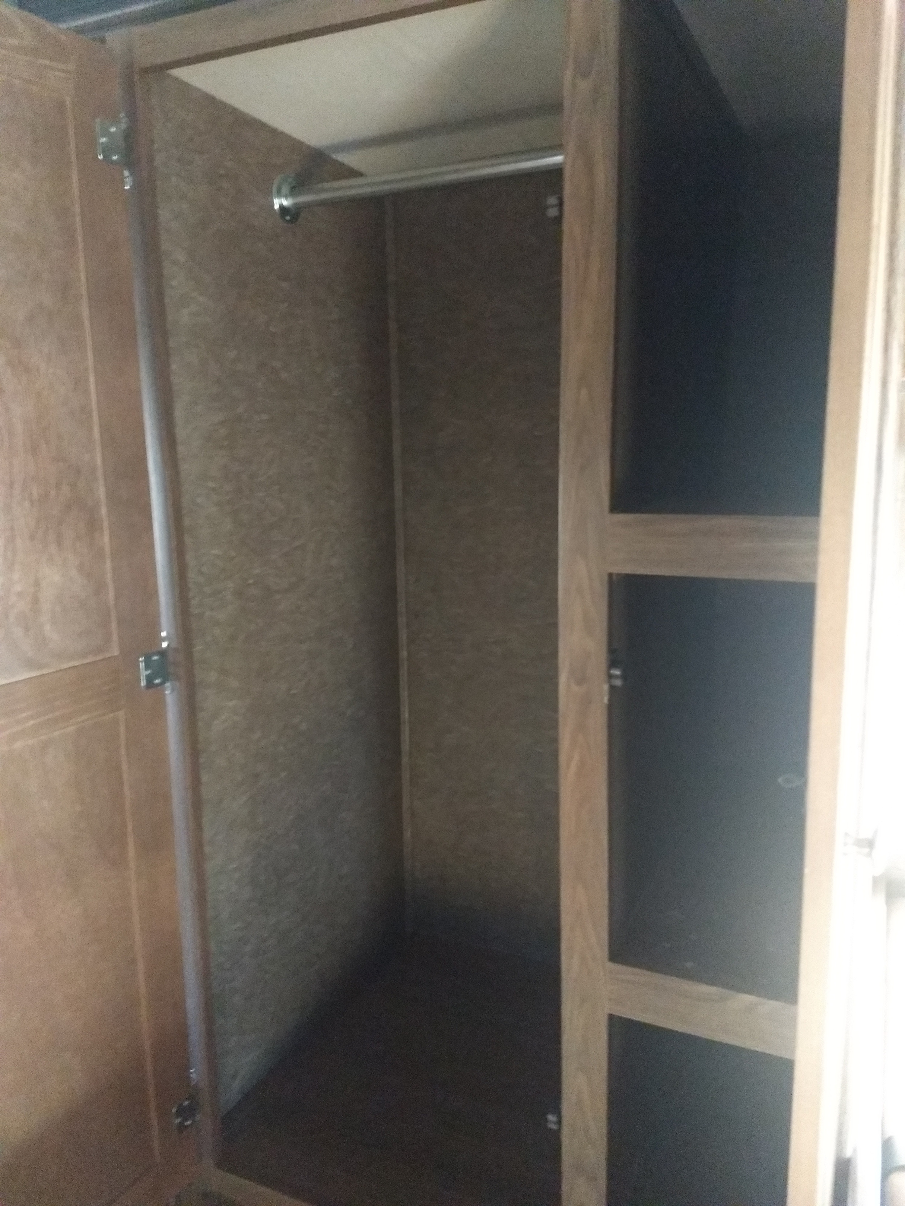 Inside an RV rental closet: half with a hanging rod, half with shelves. Features a practical wood-look interior.. Coachmen Leprechaun 2015